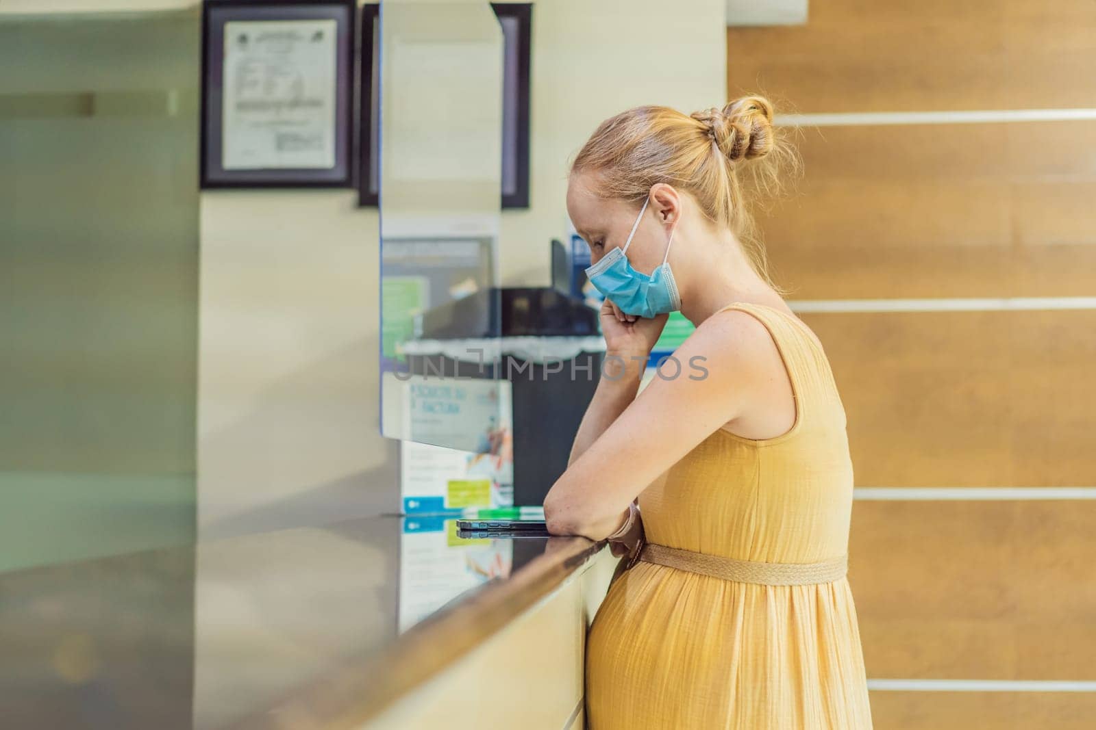 A pregnant woman stands at the hospital reception desk, embarking on a crucial phase of her maternity journey, seeking care and support in a healthcare setting.