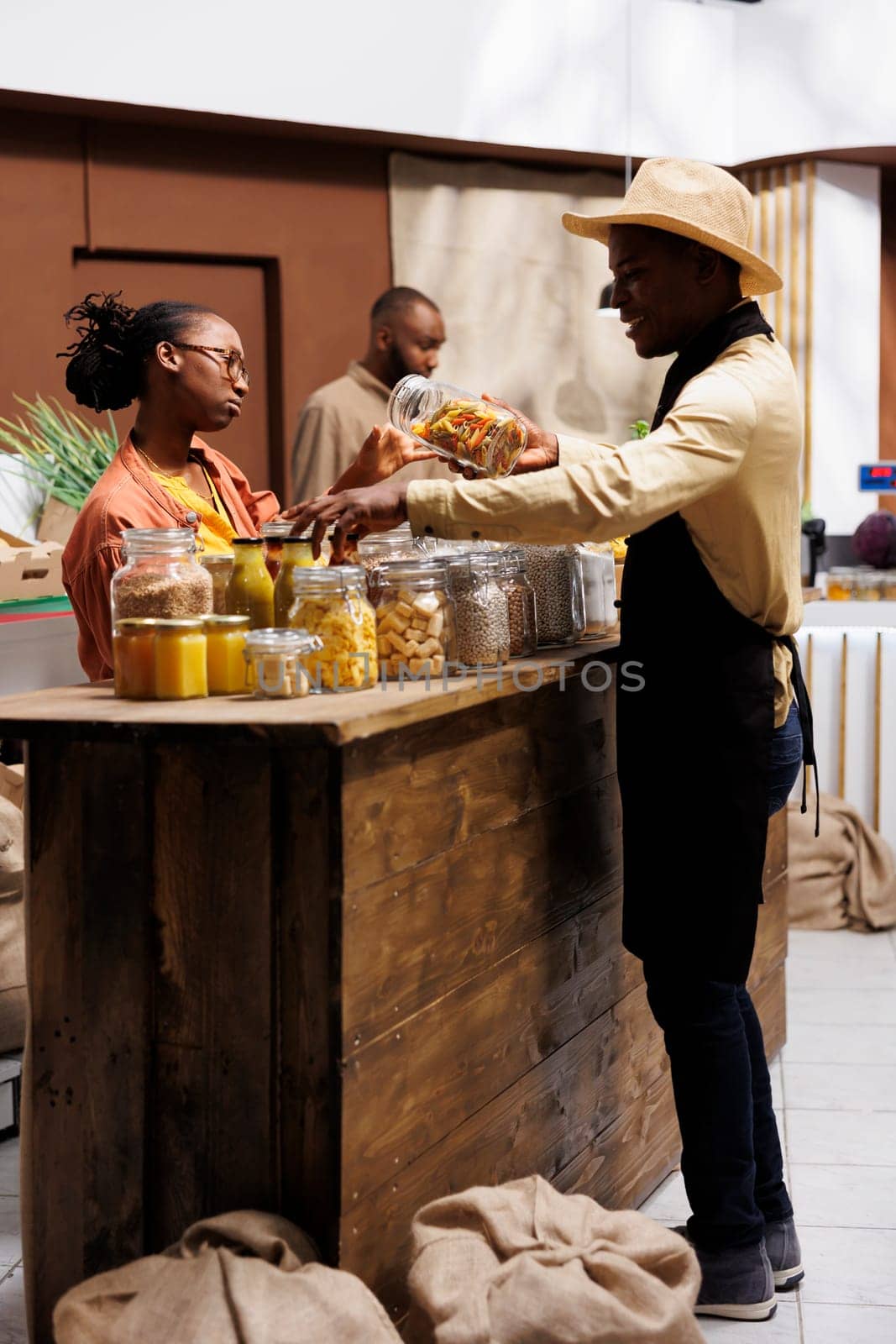 African American eco shopkeeper explaining local, organic fruits, vegetables and pantry staples to young black woman with glasses. Focus on zero waste, plastic-free, healthy, sustainable products.