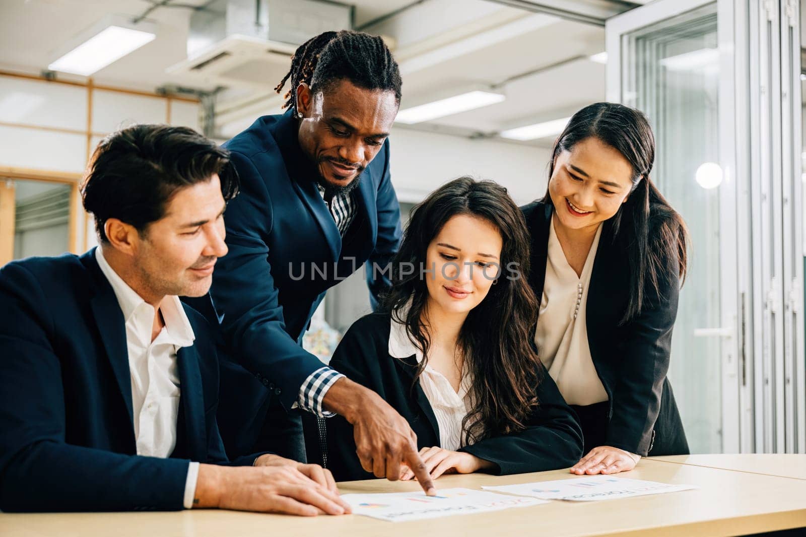 A global team, with a female leader, collaborates in a meeting room. Their teamwork is evident as they discuss financial results, share ideas, and brainstorm strategies for success.