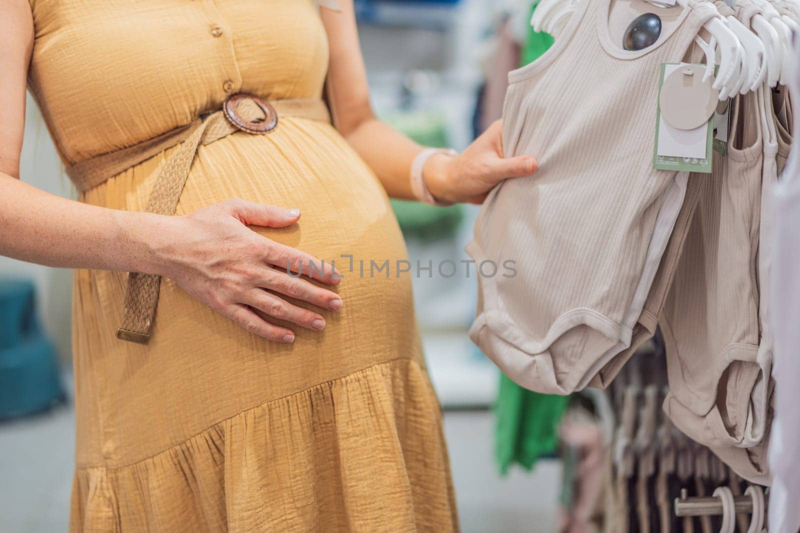 Expectant mother joyfully selects adorable clothes for her unborn baby while enjoying a shopping spree in the vibrant aisles of the shopping center.