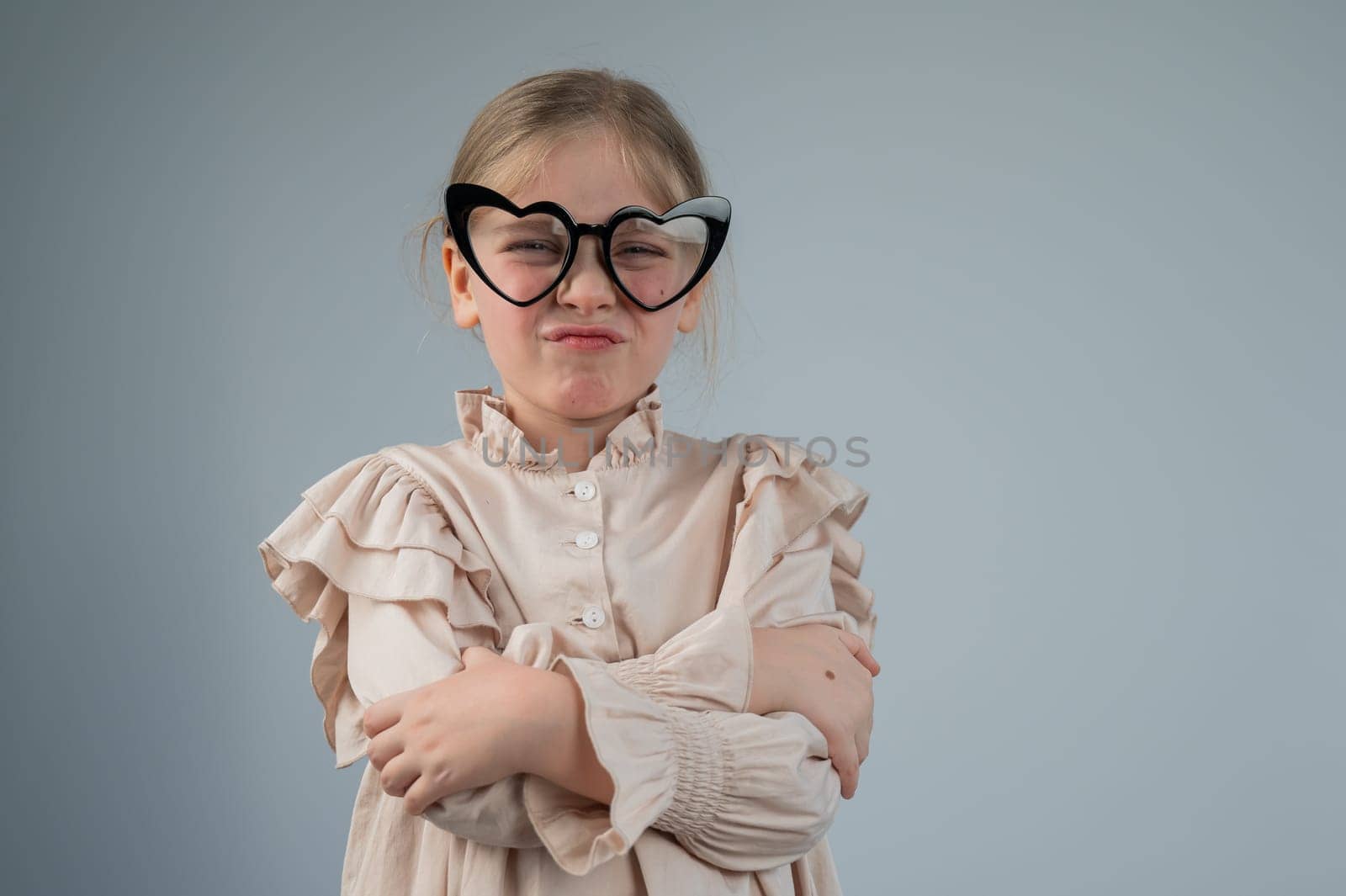 Portrait of a cute little girl grimacing wearing heart-shaped glasses on a white background. by mrwed54