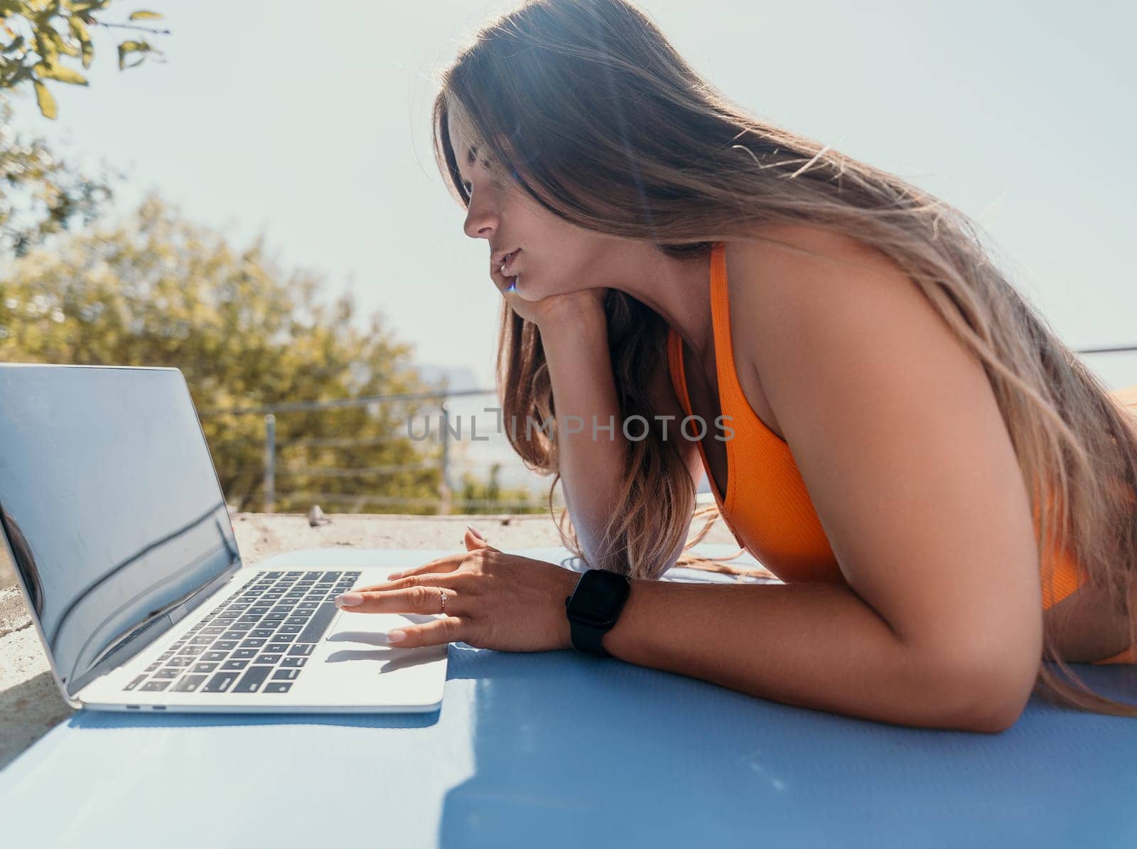 Woman laptop sea. Working remotely on seashore. Happy successful woman female freelancer working on laptop by the sea at sunset, makes a business transaction online. Freelance, remote work on vacation by panophotograph