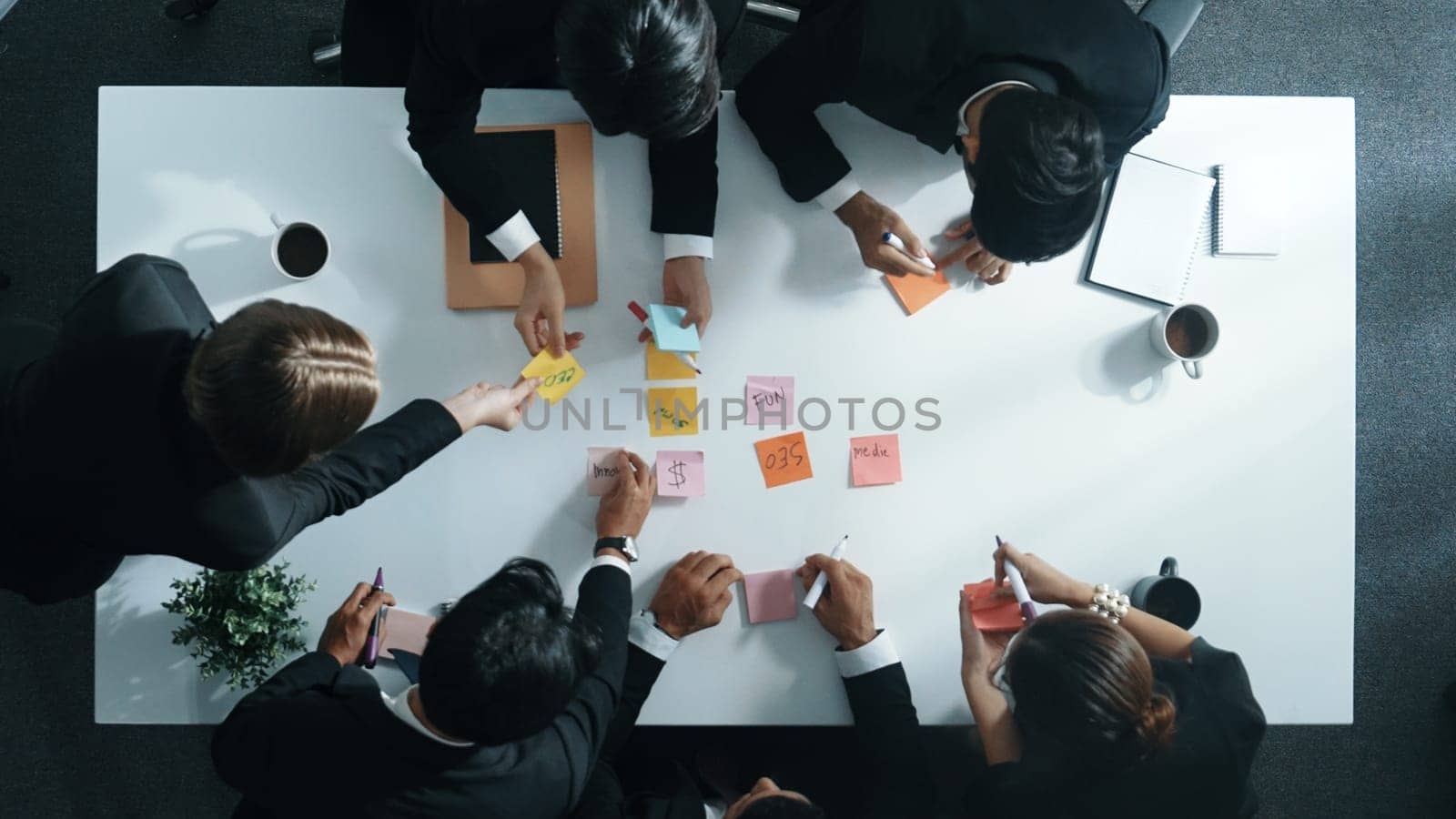 Top down aerial view of diverse business people writing marketing idea or taking a note on sticky notes. Professional executive manager group brainstorm financial plan at meeting room. Directorate.