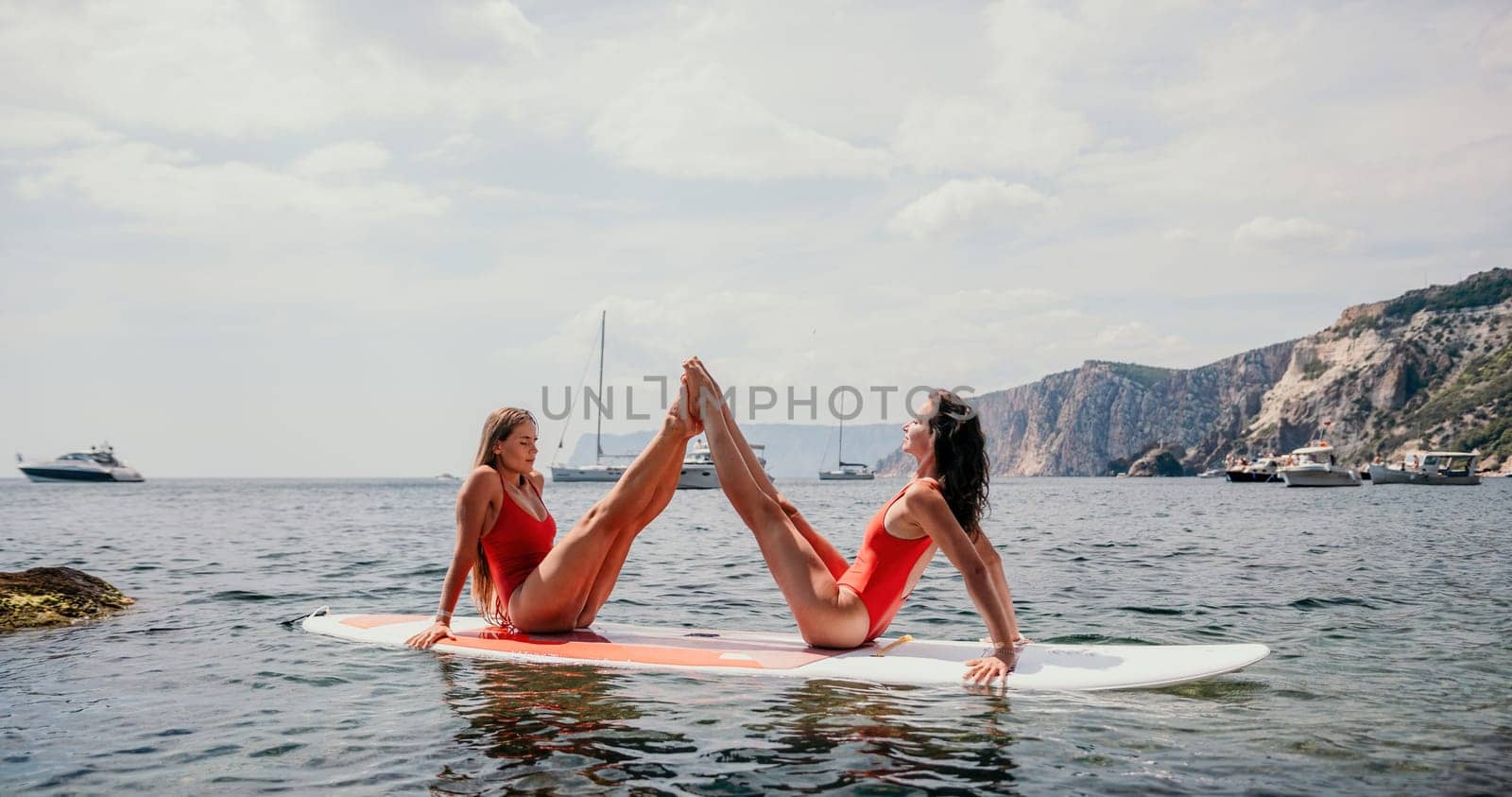 Woman sup yoga. Middle age sporty woman practising yoga pilates on paddle sup surfboard. Female stretching doing workout on sea water. Modern individual hipster outdoor summer sport activity