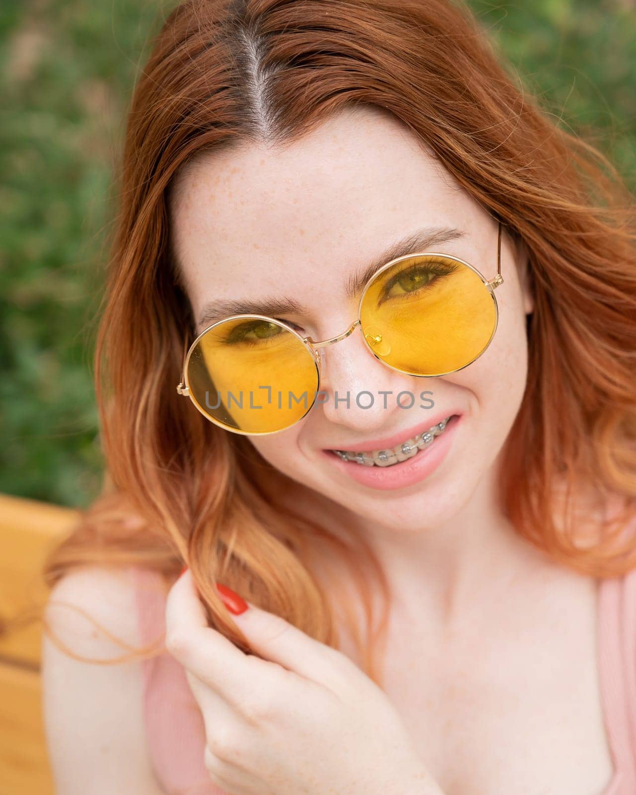 Beautiful young woman in yellow sunglasses smiling showing off braces on her teeth. Vertical photo