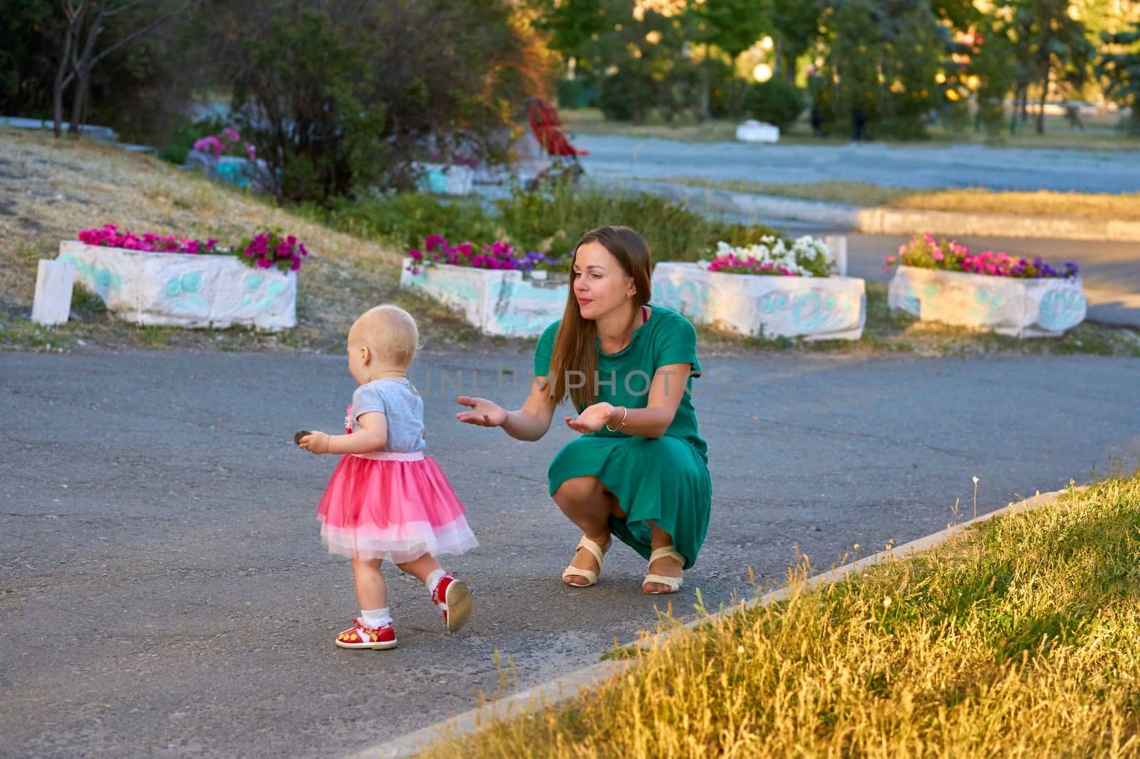 Cute mother with a charming baby daughter walks in the city park by jovani68