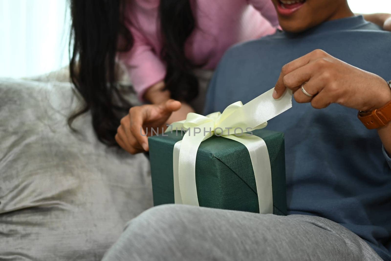 Happy man opening opening gift box from his girlfriend. People, celebration and holidays concept.