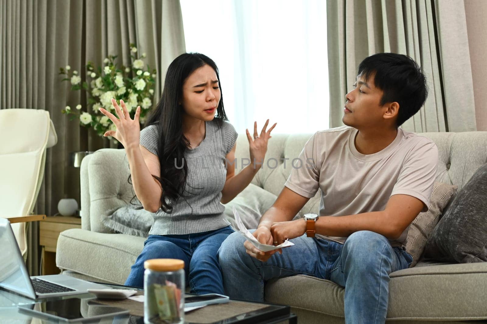 Stressed couple quarreling, arguing about serious financial problems at home by prathanchorruangsak