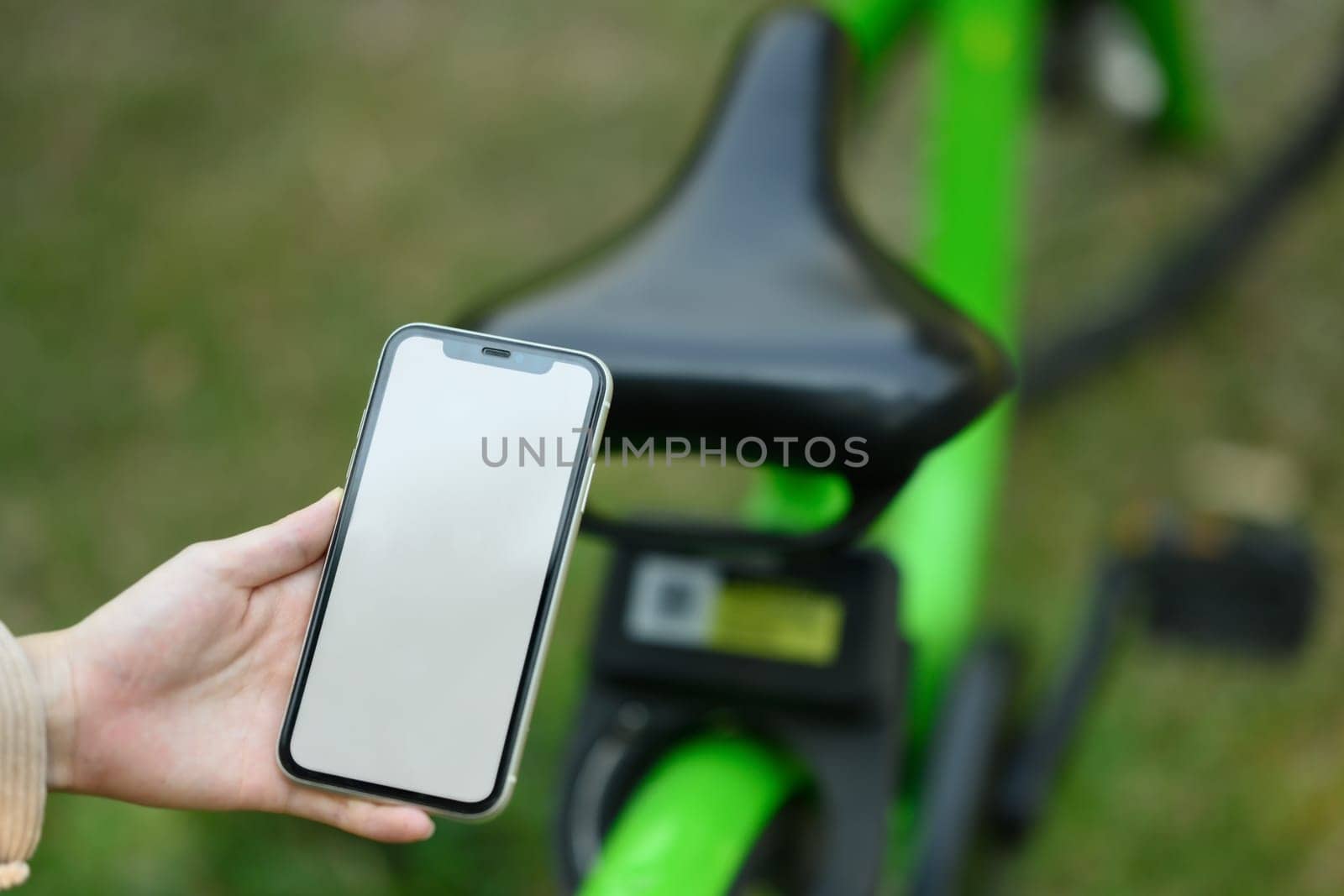 Closeup young woman using mobile app for rent electronic bicycle. Ecological transport concept.