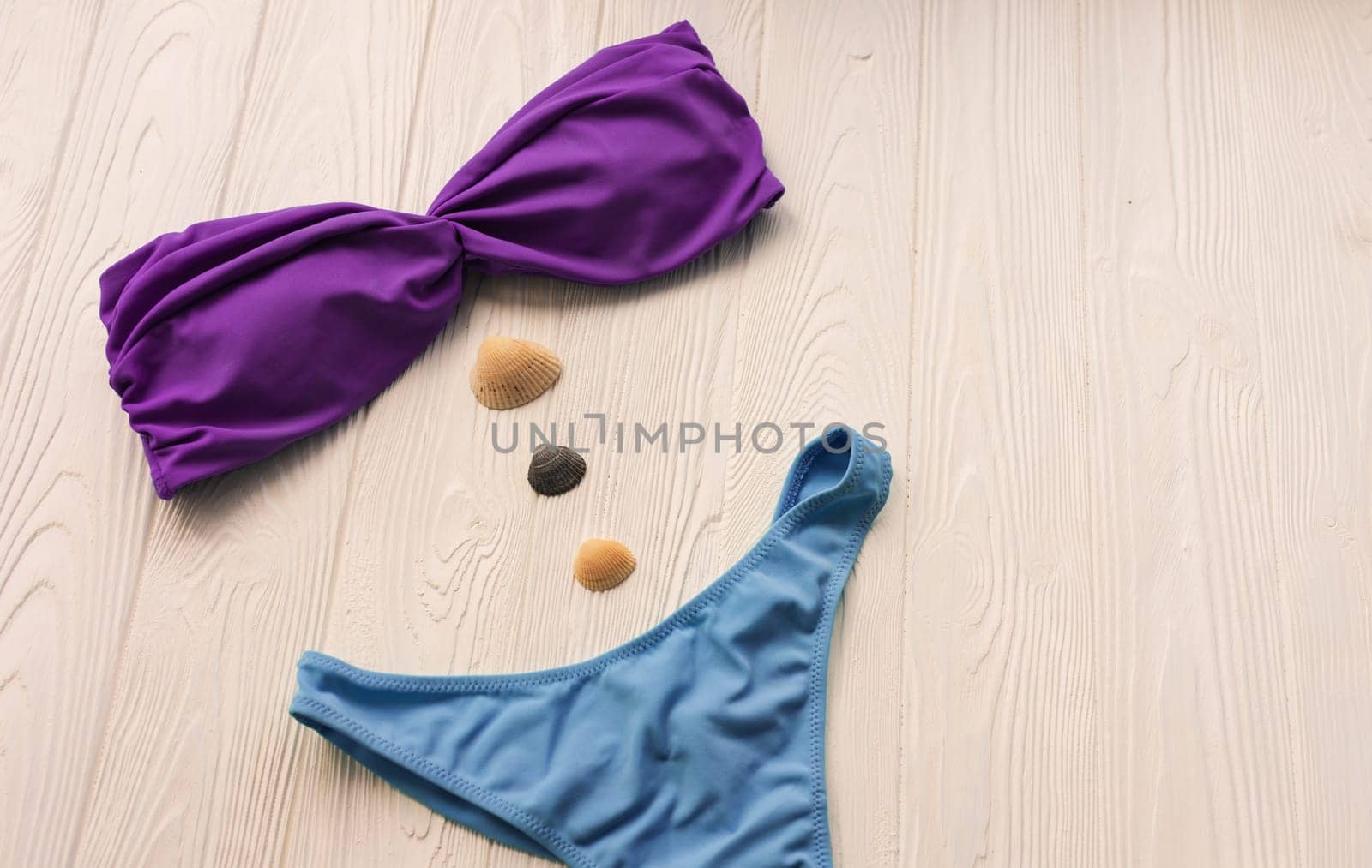 Women split multicolor blue swimsuit bikini. Summer background mockup template. pattern top view above swimwear white wooden background. accessories clothes beach. Women summer design vacation