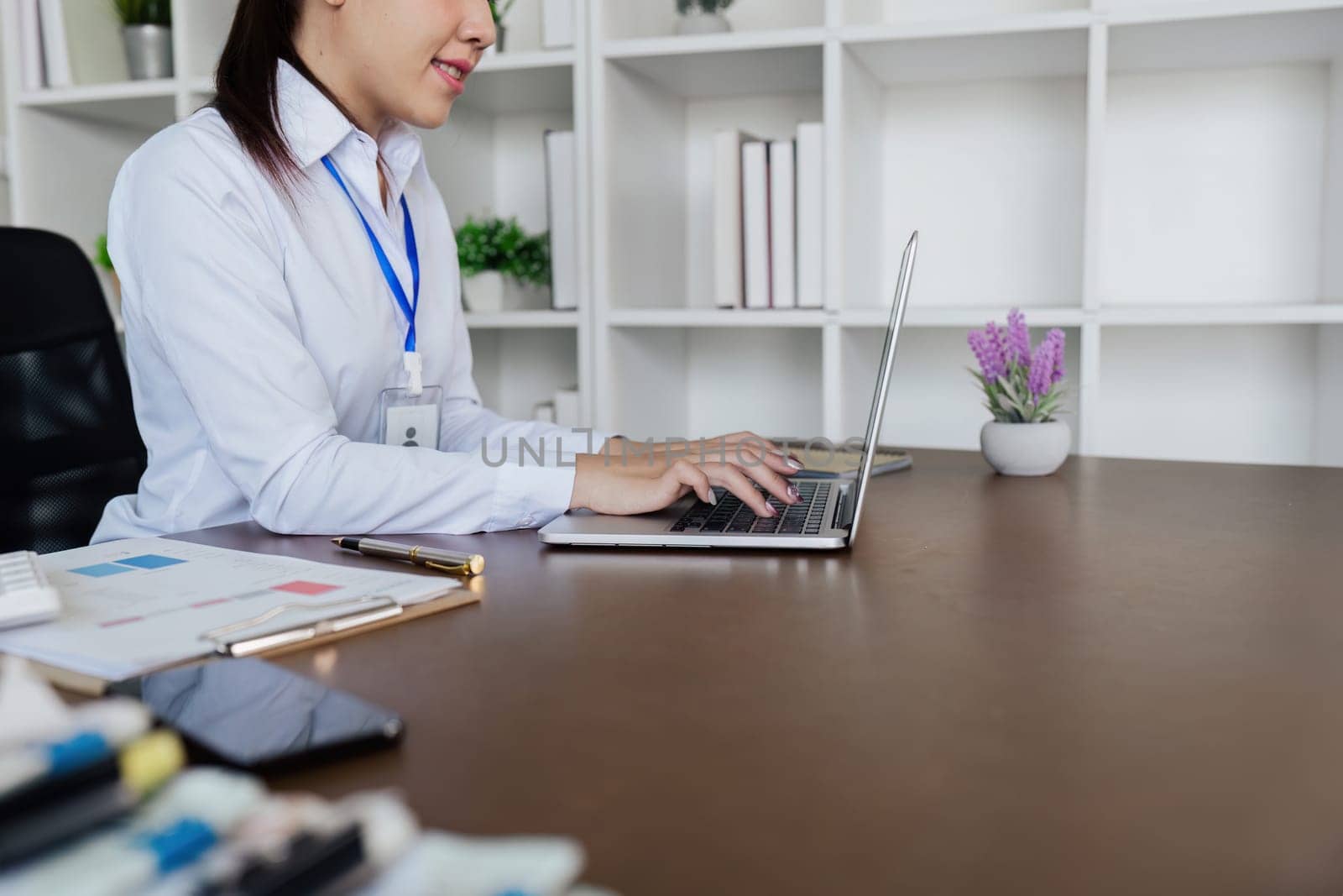 Businesswoman analyzing marketing strategy on laptop, typing work on laptop by itchaznong