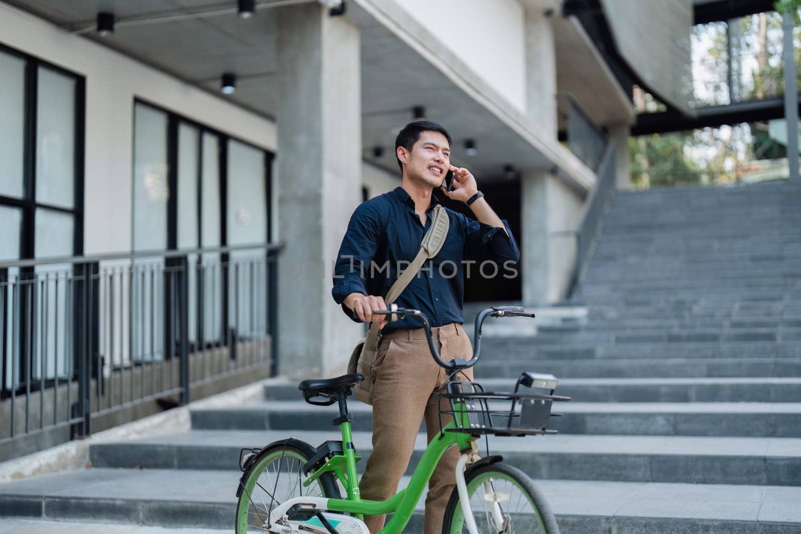 A man in a suit is standing next to a bicycle with a basket on it. He is looking at his cell phone