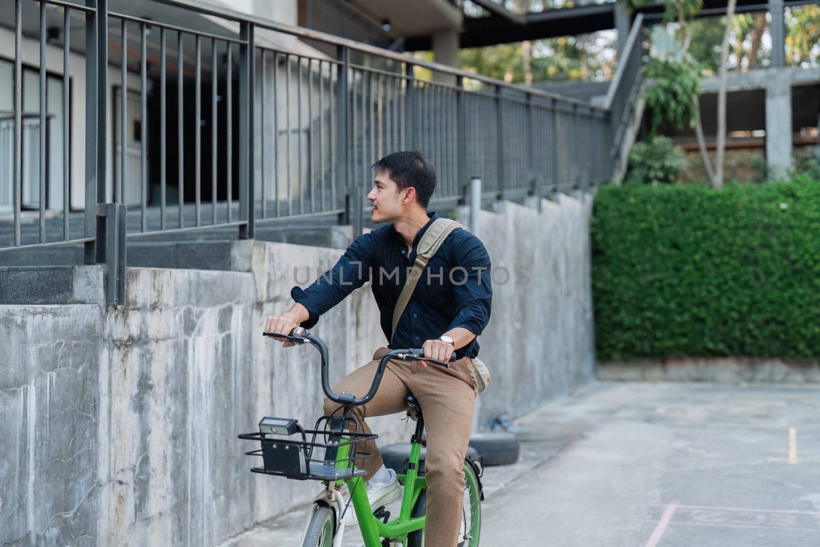 A man in a suit is riding a green bike with a basket. He is wearing a watch and a backpack