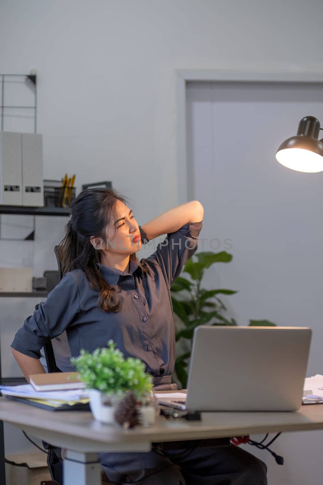 Young businesswoman who is tired from sitting for a long time in the office by wichayada