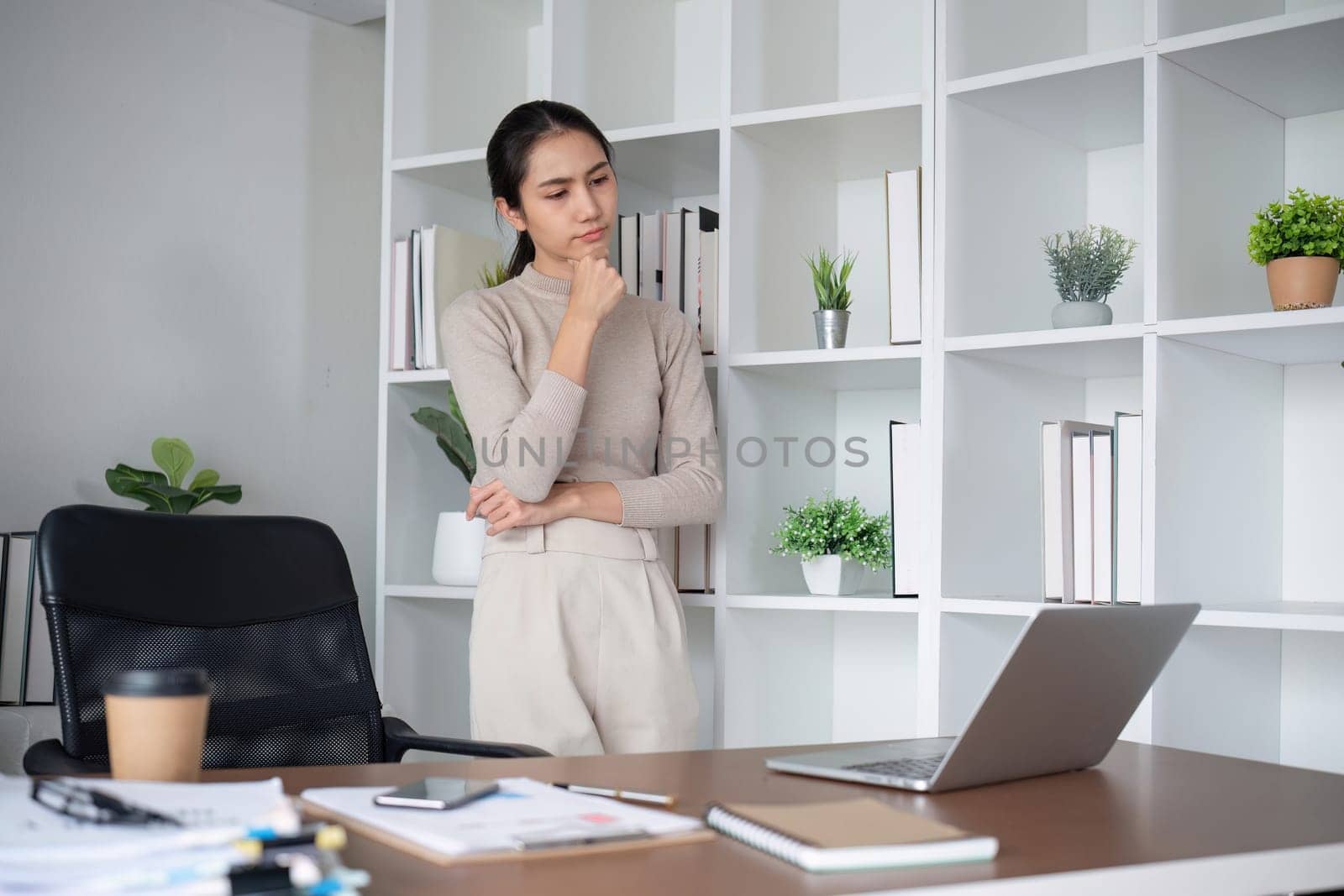 Asian businesswoman feeling tired and stressed over an unsuccessful business while working in a home office decorated with soothing green plants..
