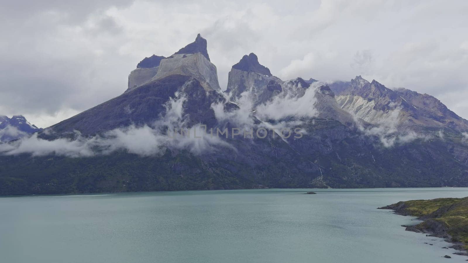 Time-lapse of clouds over a lake with Cuernos del Paine mountain in the background.