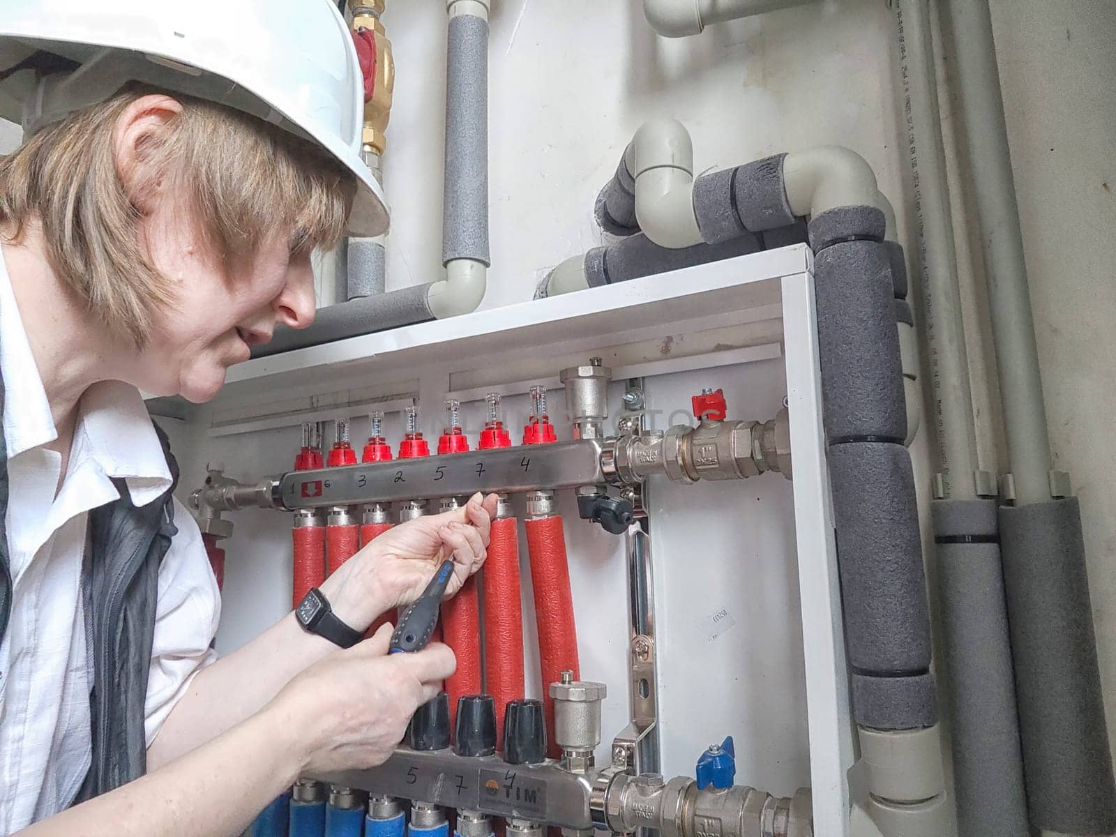 Female Technician Adjusting Industrial Water Filtration System. Middle aged Woman services a water filtration unit