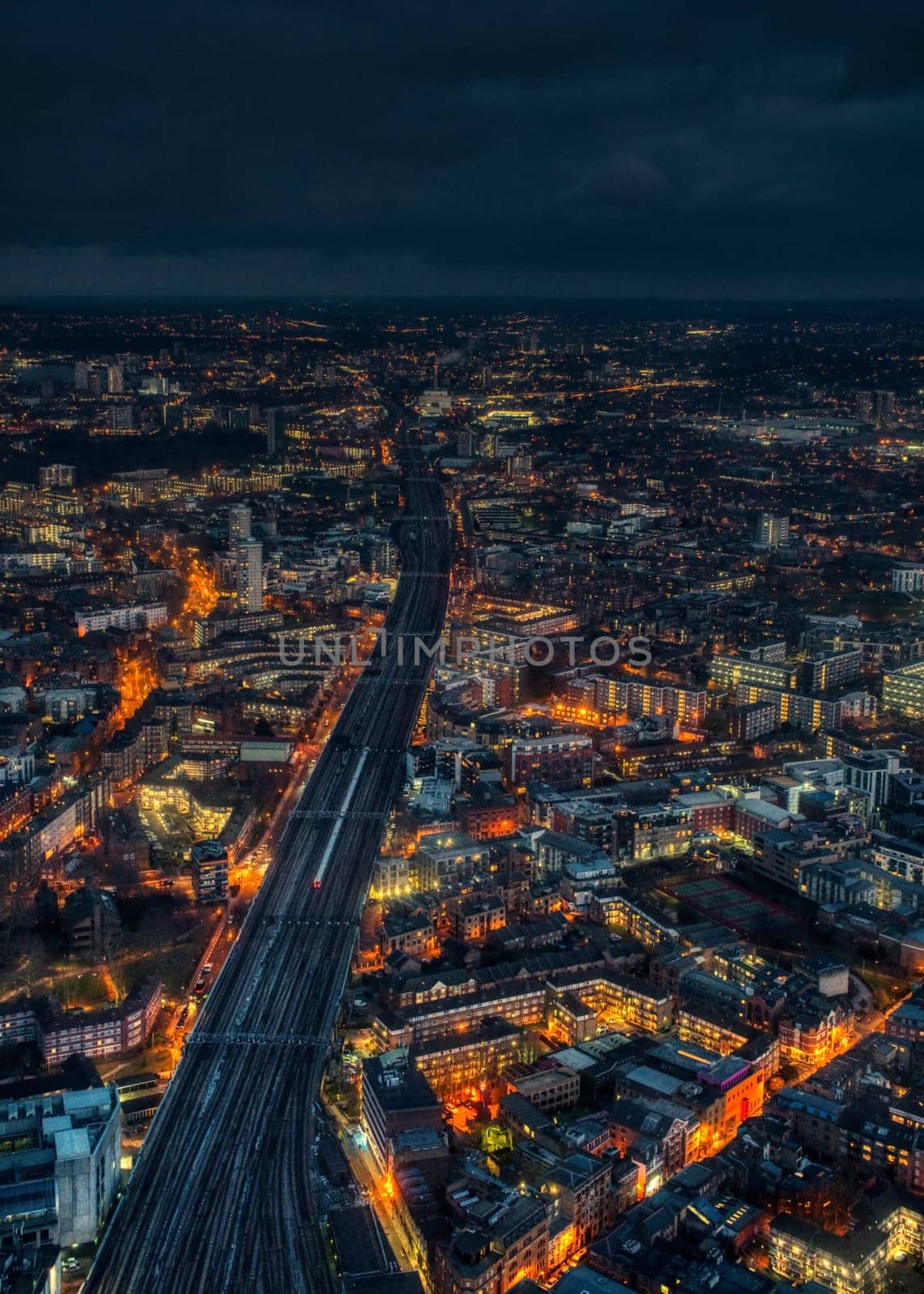 Aerial night view of east London, wide railway track with one train on it in middle by Ivanko