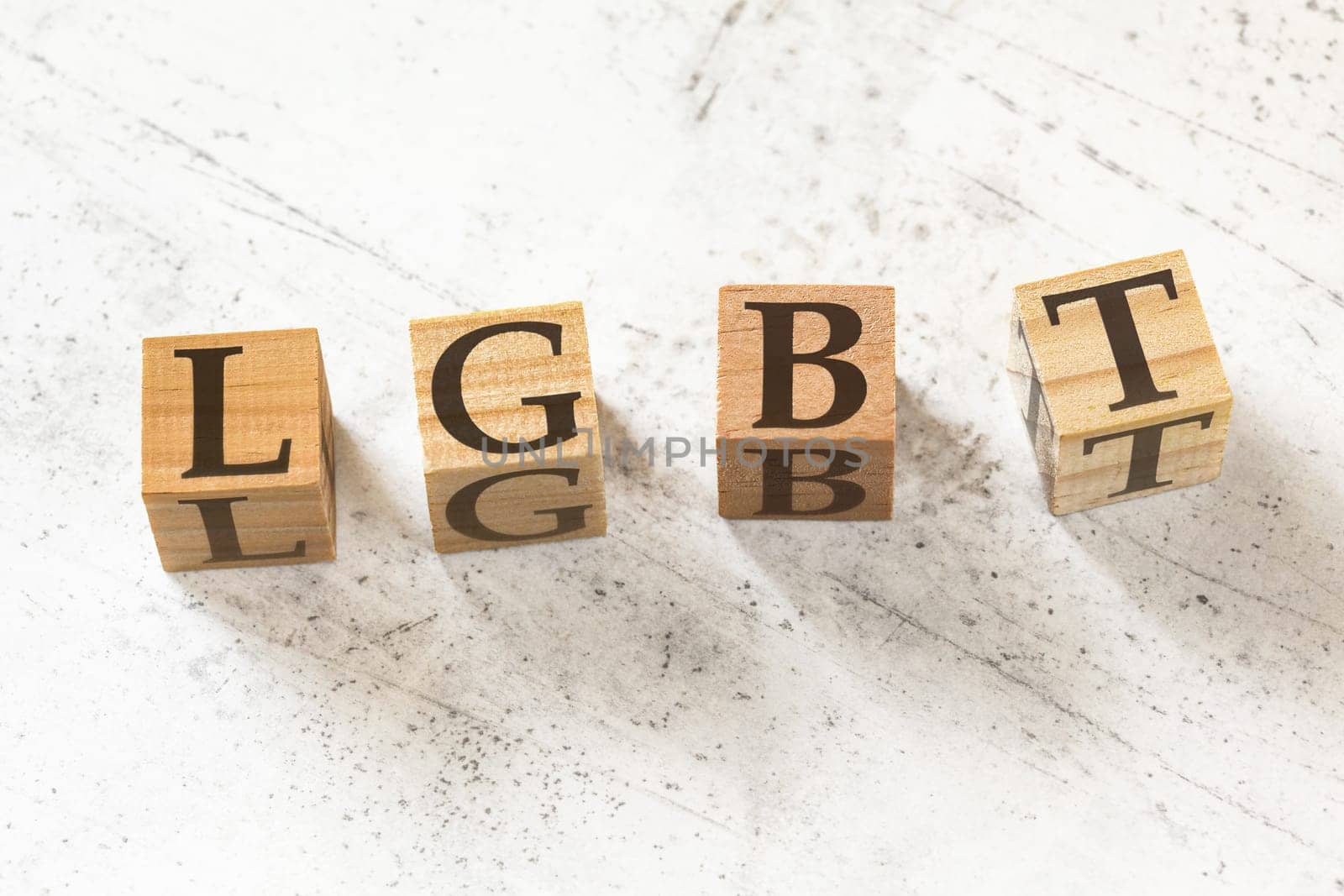 Four wooden cubes with letters LGBT (meaning lesbian, gay, bisexual, and transgender) on white working board.