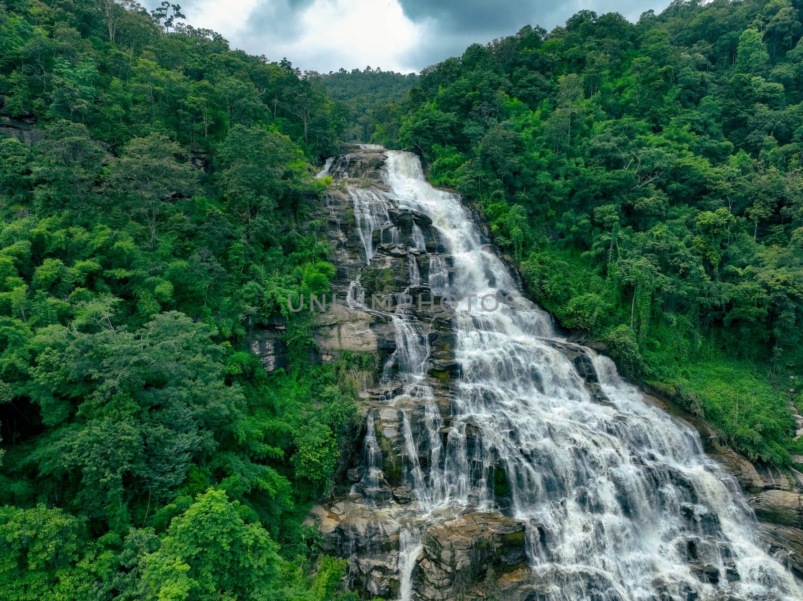 Large waterfall with lush green forest in the background. Nature landscape. Water is crystal clear and trees are full and green. Scene is serene and peaceful. Waterfall in Doi Inthanon National Park