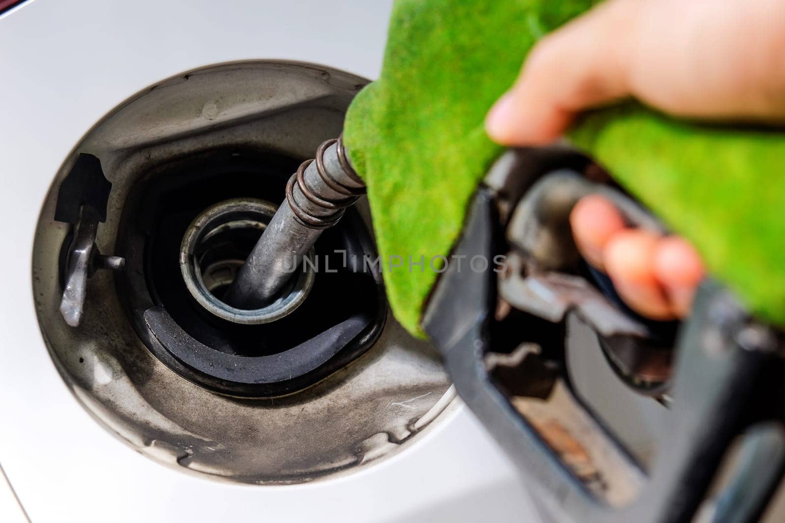 Close up image of hand refilling a car with fuel at a gas station, green fuel nozzle,energy concept