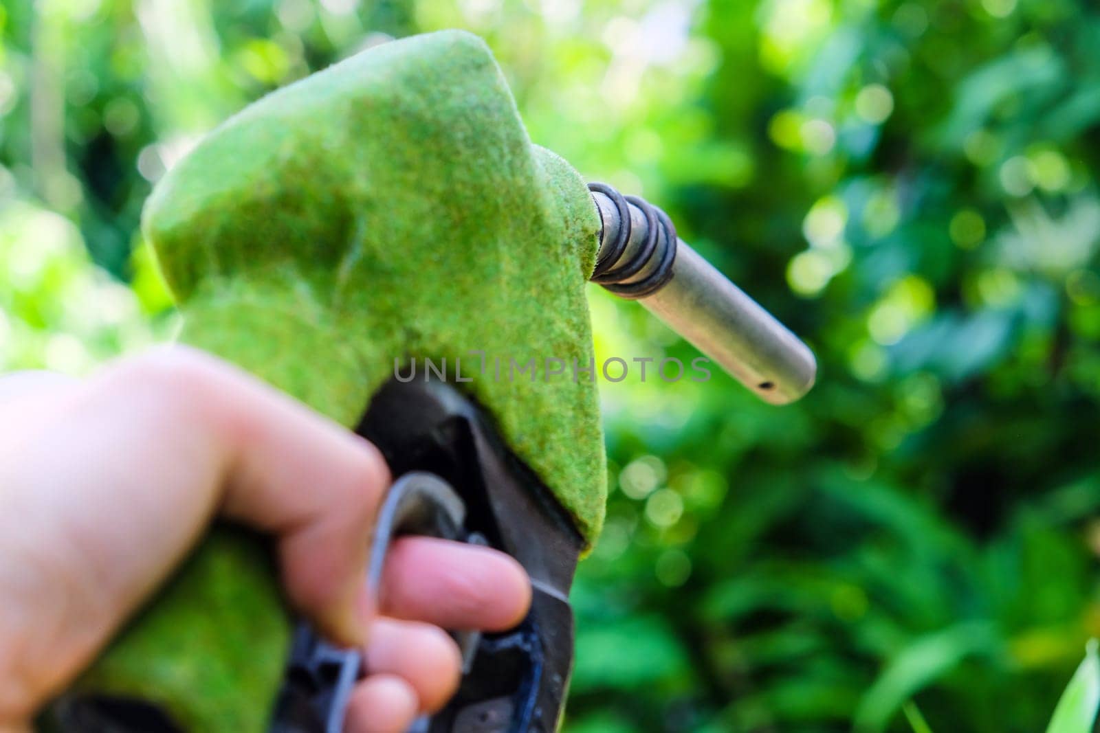 Hand holding green fuel nozzle by ponsulak