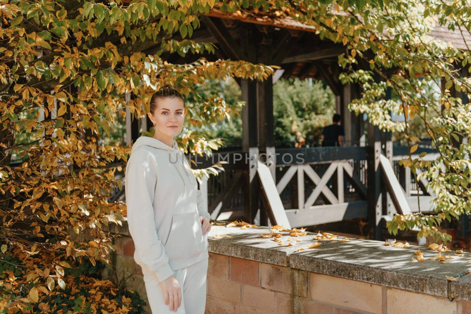 Beautiful elegant woman standing in autumn park with yellow leaves outdoor. Beauty Romantic Girl Outdoors enjoyitumn yellow leaves. Portrait of joyful woman in park during fall. Happy ng nature. Sun light on sunset. Warm toned art work. Portrait of romantic female by Andrii_Ko