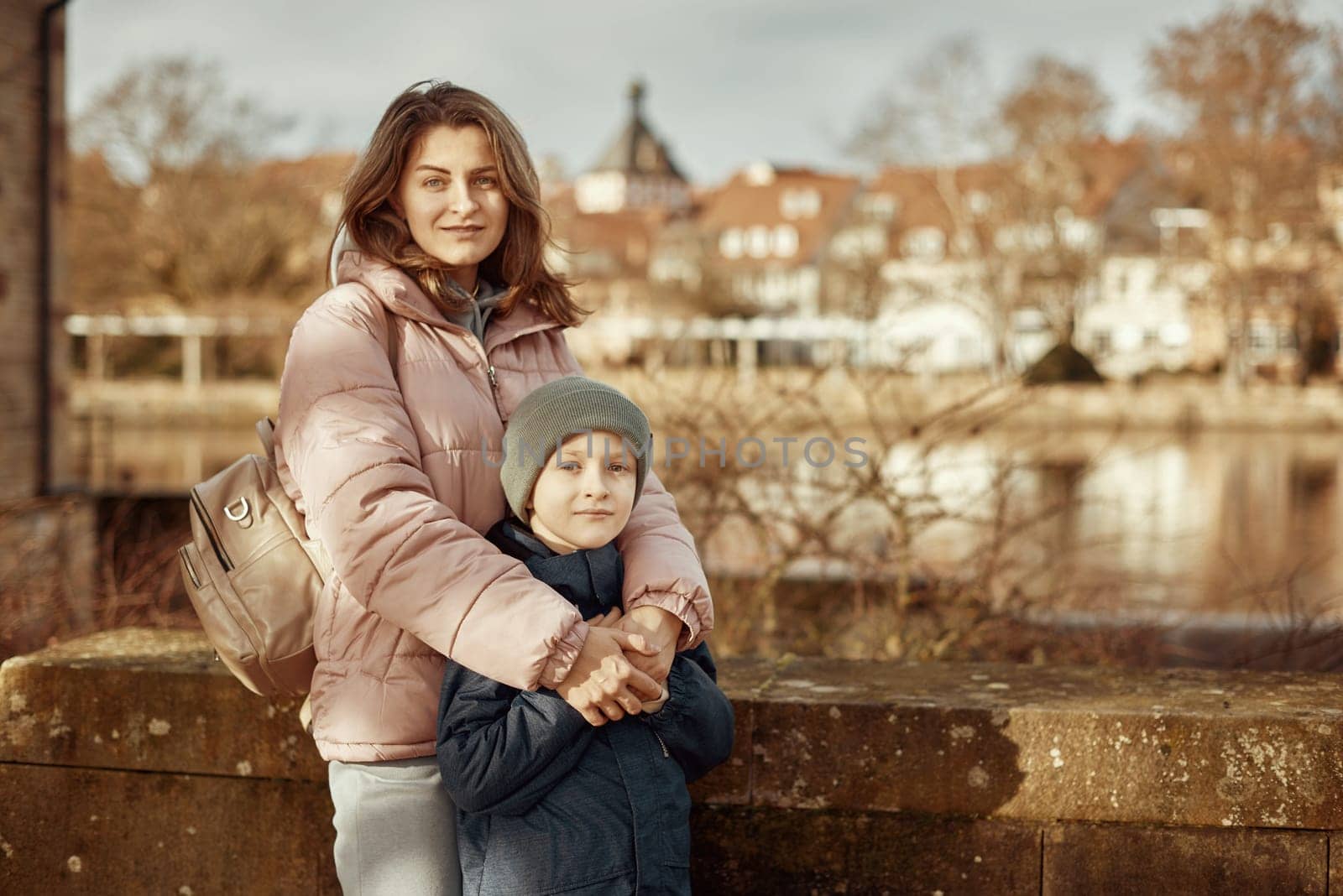 Riverside Family Harmony: Mother, 30 Years Old, and Son - Beautiful 8-Year-Old Boy, Standing by Neckar River and Historic Half-Timbered Town, Bietigheim-Bissingen, Germany, Autumn by Andrii_Ko