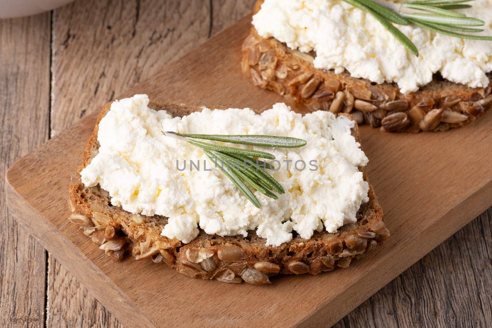Home made rye bread on a wooden cutting board with curd cheese.