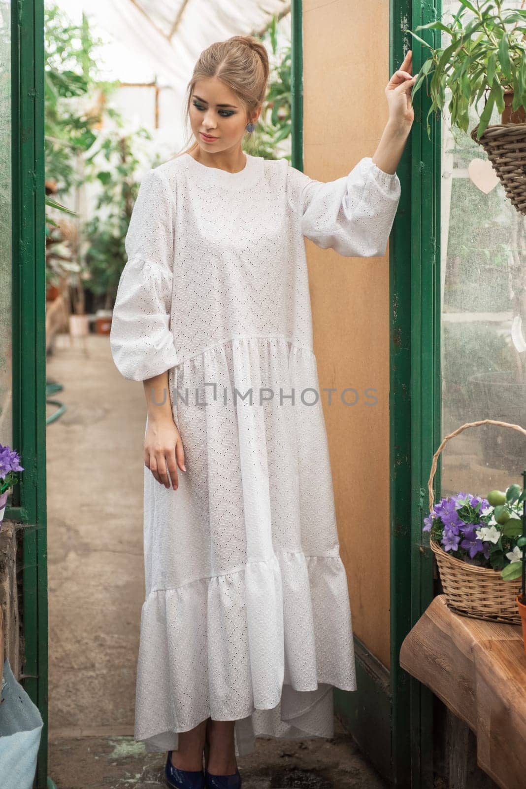 Young woman in white dress at a glass greenhouse
