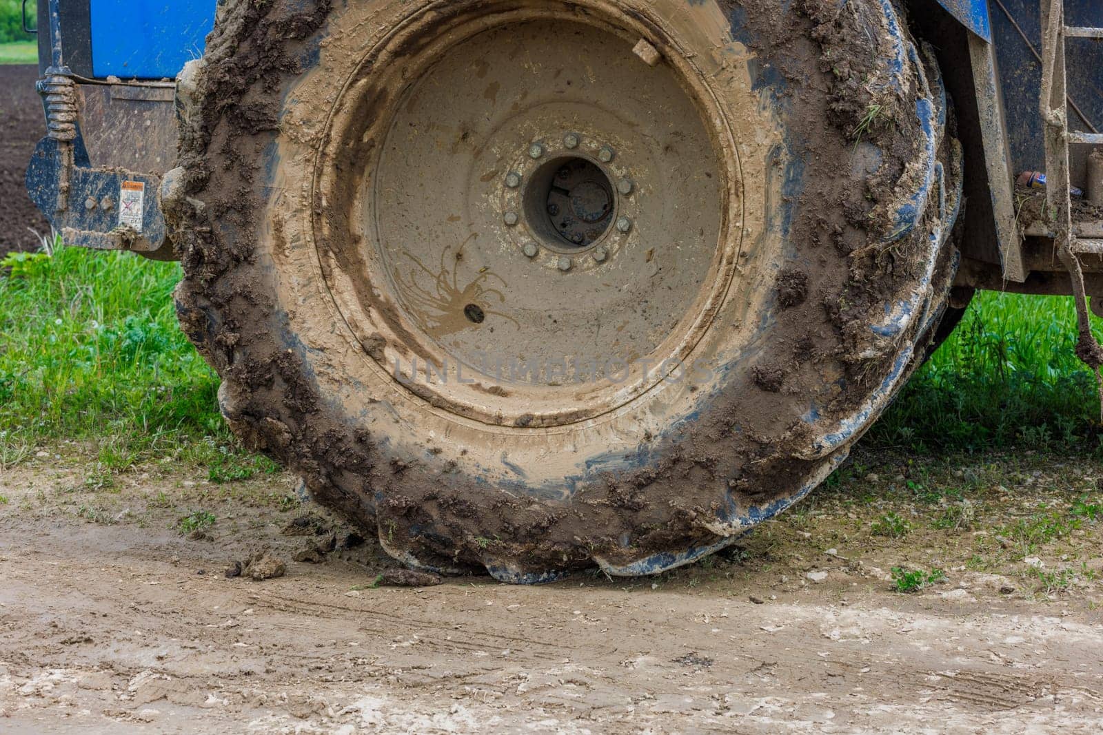 dirty double wheel of a big agriculture tractor on dirt road at summer day by z1b