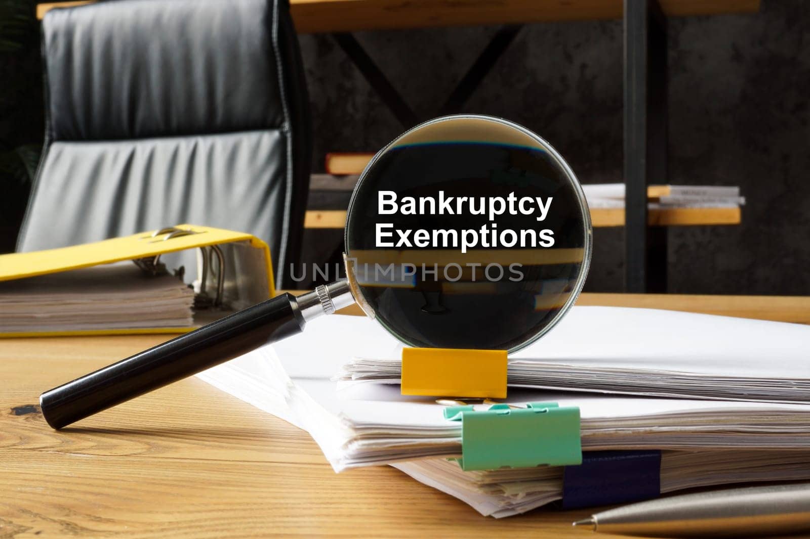 Bankruptcy exemptions concept. Magnifying glass lies on a stack of papers.