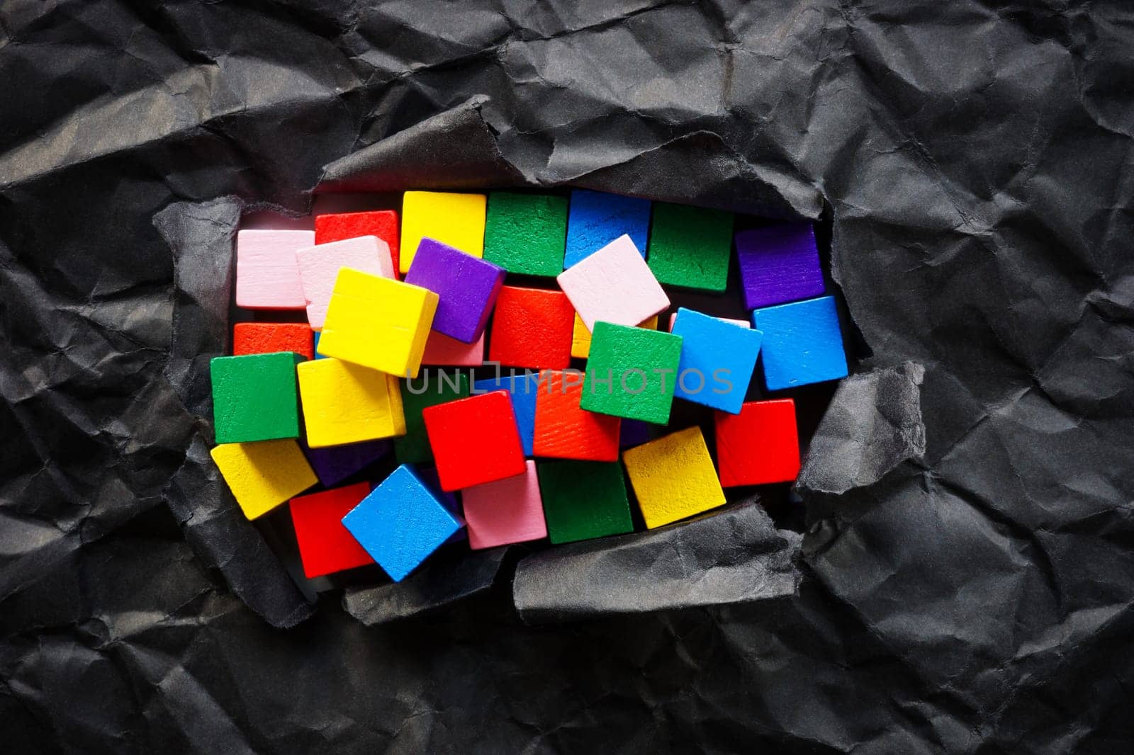 Colored cubes and torn black paper. Diversity and positive thinking. by designer491