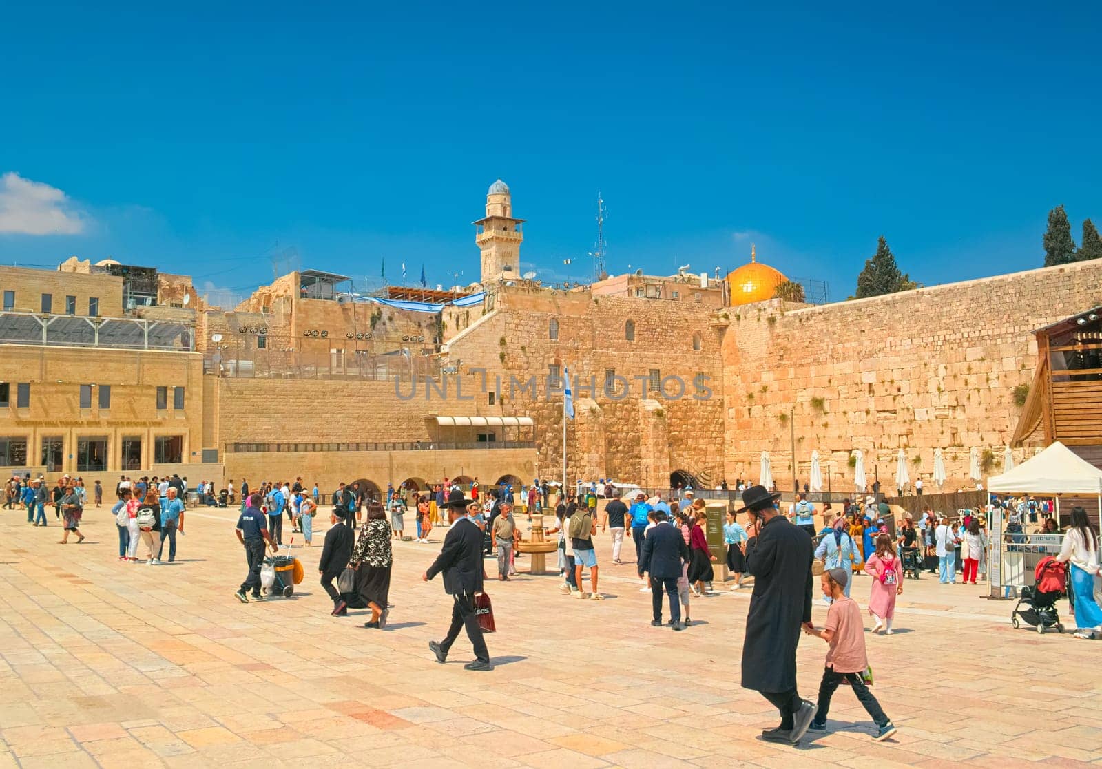 Jerusalem, Israel - 9 May, 2023: View of the Western Wall (Wailing Wall) in the old city of Jerusalem. Religious Jews in traditional clothing walking near by Israel's most visited place.