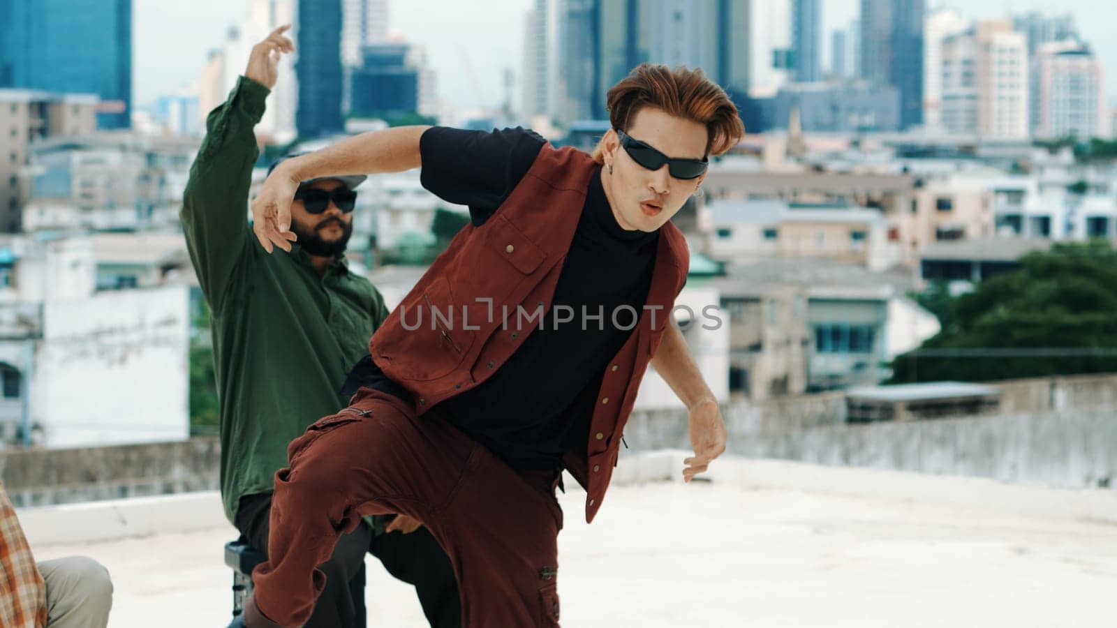 Motion shot of B-boy dance performance by professional street dancer at rooftop with sky scrapper, city view. Attractive asian hipster show energetic footstep. Outdoor sport 2024. Closeup. Endeavor.