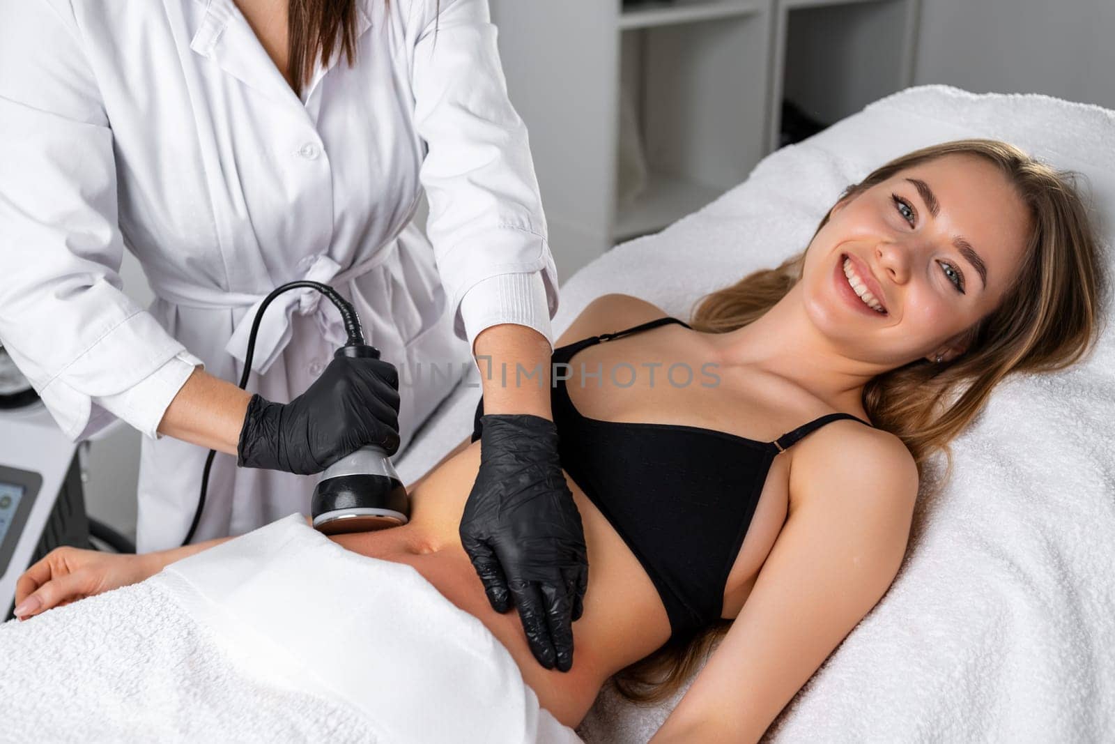 Young smiling woman during ultrasound cavitation body contouring treatment procedure by vladimka