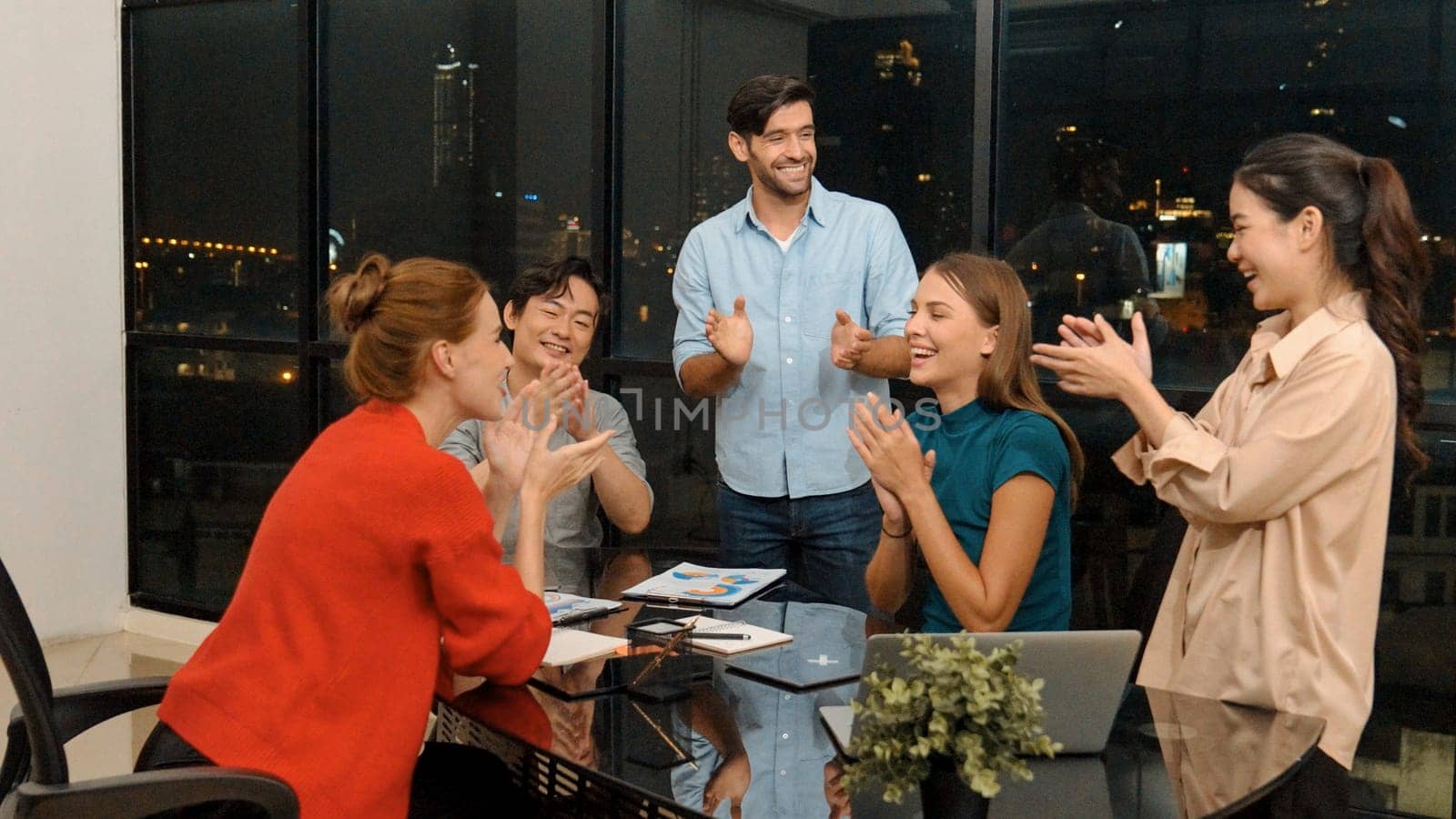 Businesspeople putting hands together and clapping hands to celebrate successful project at modern office with night city view. Group of manager with stacks of hands. Teamwork, trust. Tracery