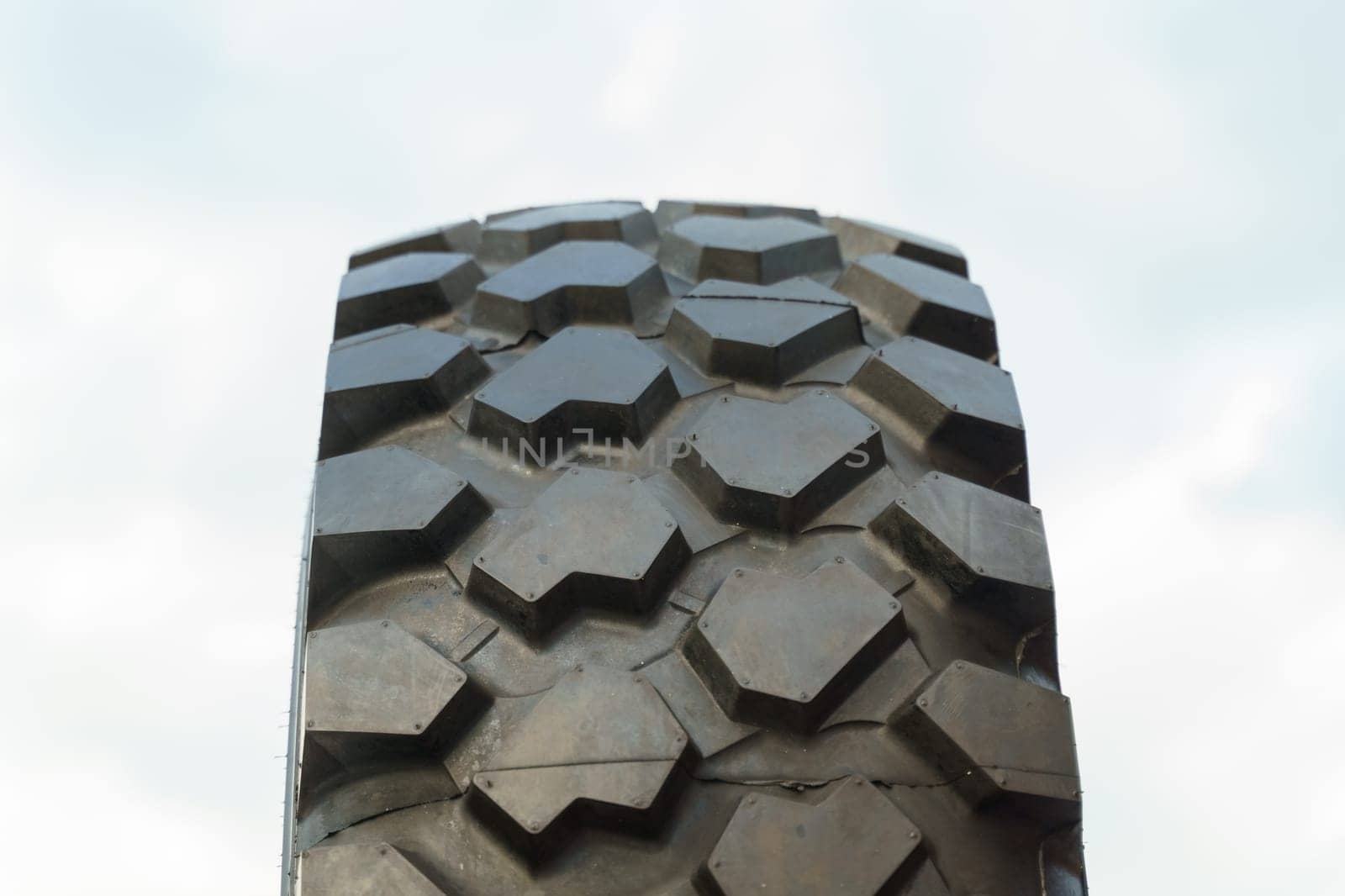 Detailed view of a tire with treads visible, set against a clear blue sky background.