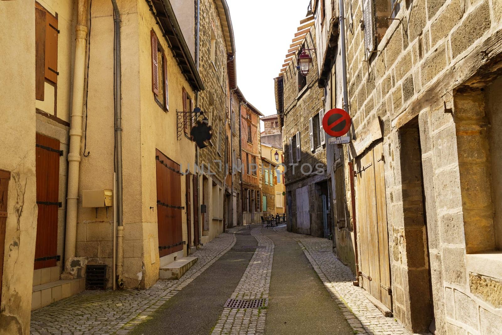 A narrow street with a stop sign positioned in the middle of it, creating a point of pause for vehicles traveling through the urban area.