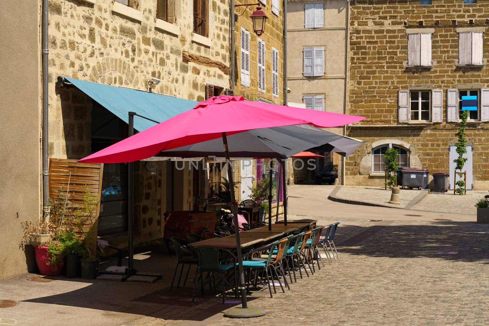 A pink umbrella rests against the side of a building, adding a pop of color to the urban scene.