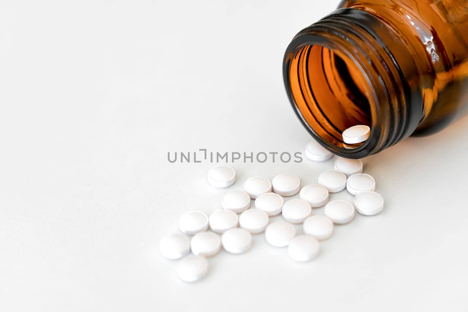 Medication Close-Up: White Pills and Brown Glass Vial Arranged on Table, Copy Space, Close-Up, Healthcare Concept. by Laguna781