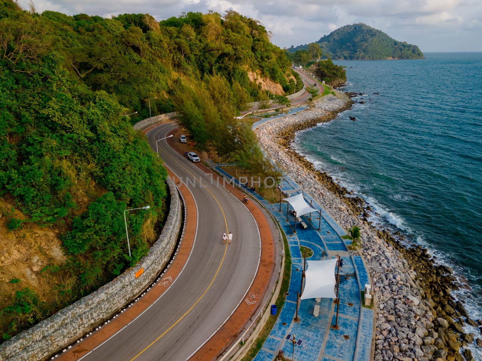 car driving on the curved road of Thailand. road landscape in summer. it's nice to drive on the beachside highway. In Chantaburi Province Thailand, couple men and women walking on the road