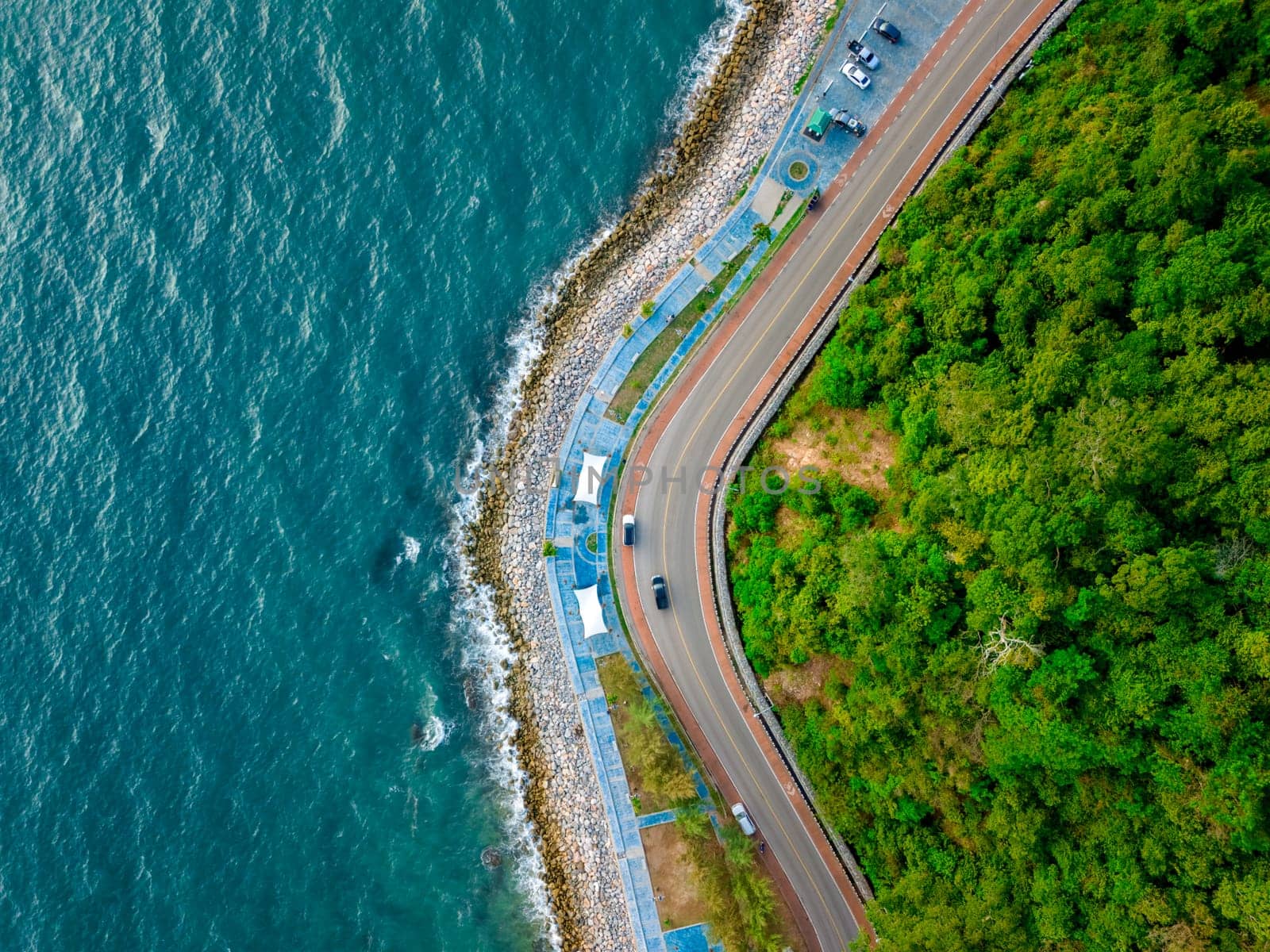 car driving on the curved road alongside the ocean beach road of Thailand. road landscape in summer. it's nice to drive on the beachside highway. Chantaburi Province Thailand, top view drone view