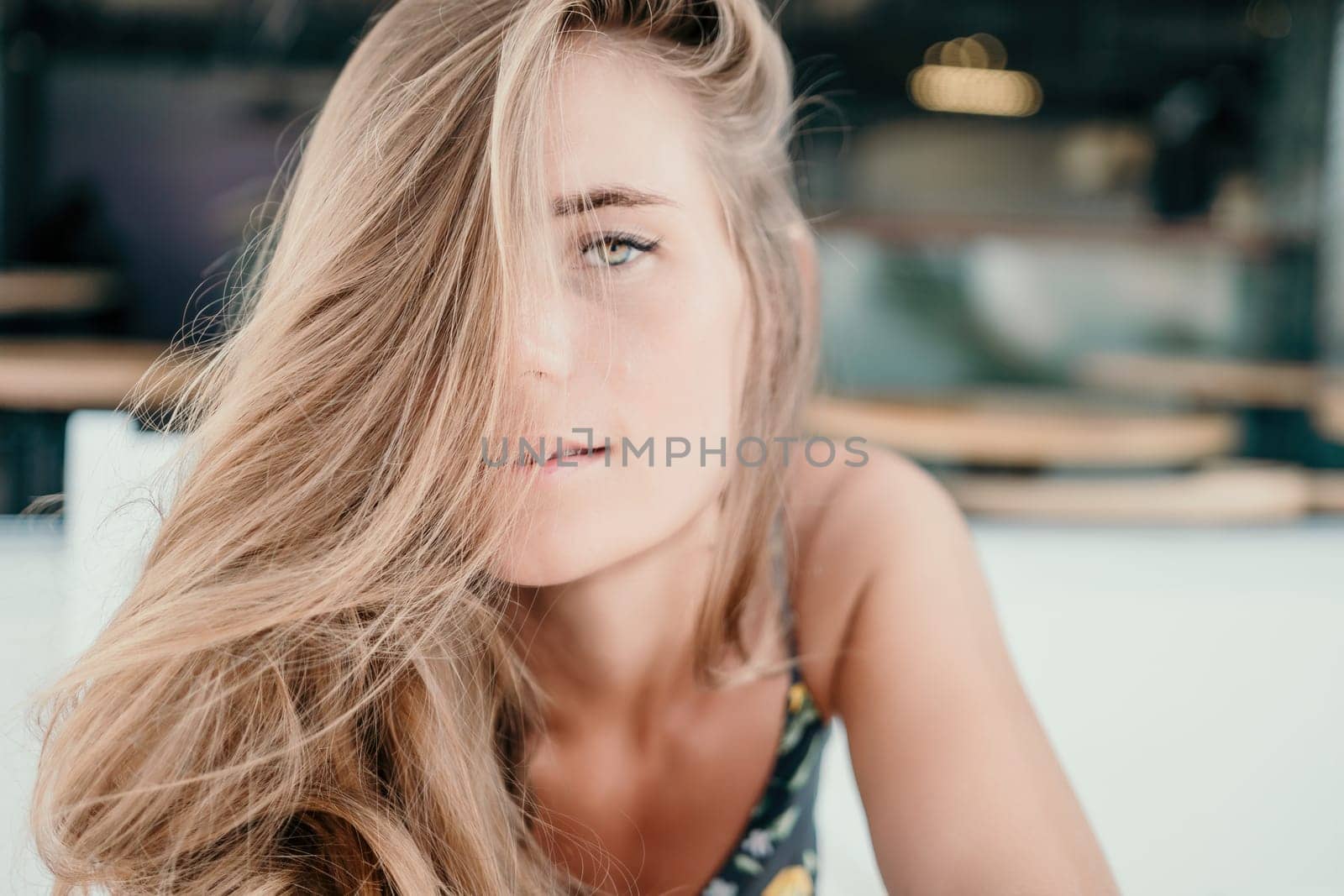 Happy woman portrait in cafe. Boho chic fashion style. Outdoor photo of young happy woman with long hair, sunny weather outdoors sitting in modern cafe