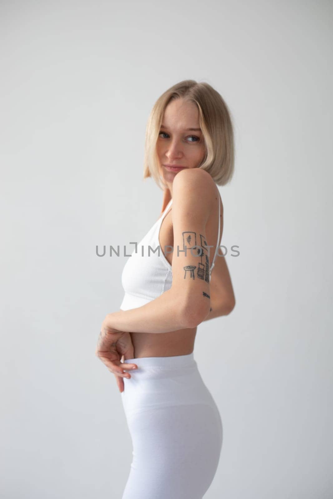 Blonde girl posing on a white background in a top and leggings. High quality photo