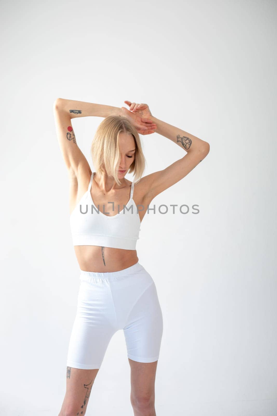 Blonde girl posing on a white background in a top and leggings. High quality photo