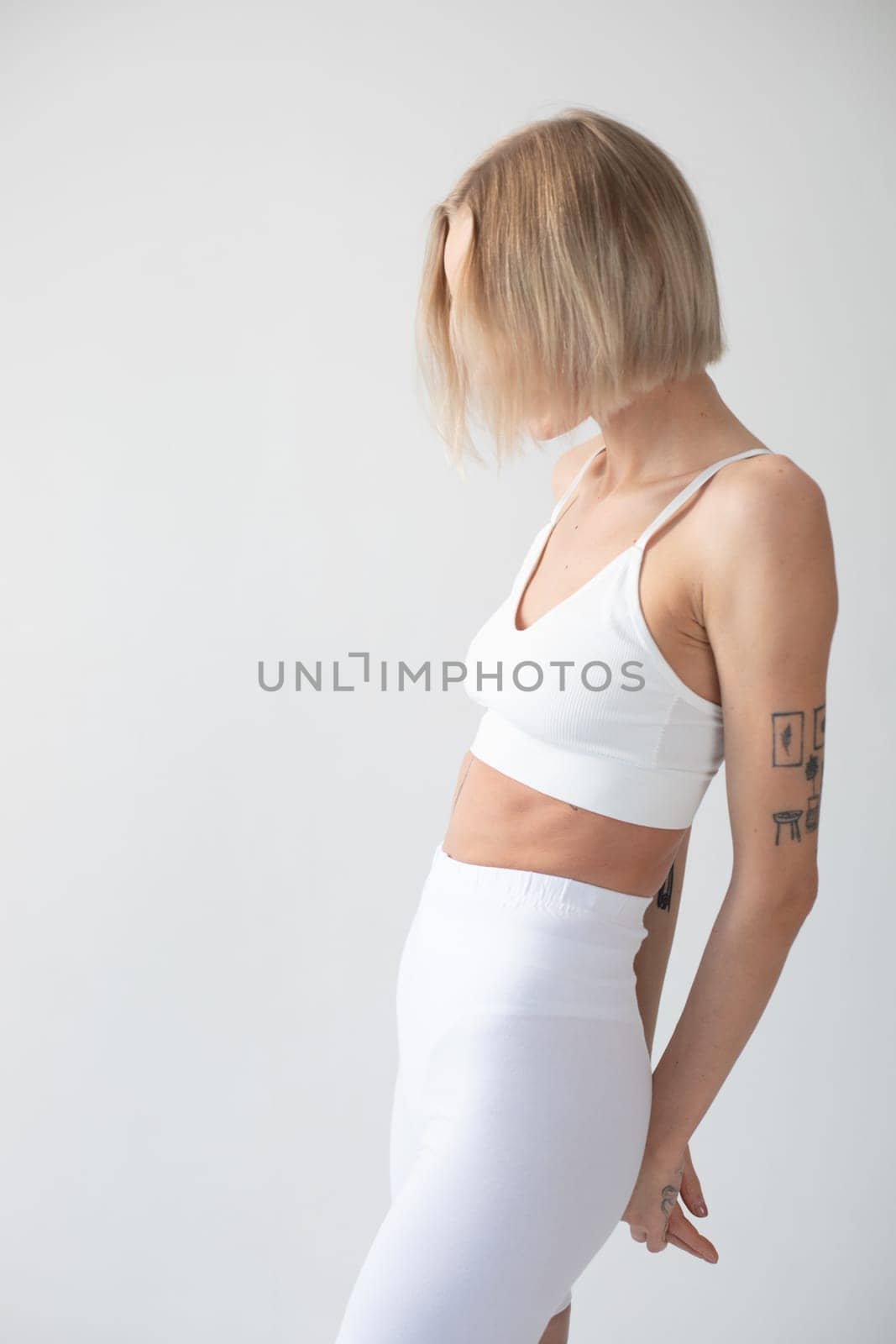 Blonde girl posing on a white background in a top and leggings. High quality photo