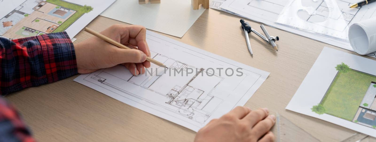 Closeup of architect engineer hand using ruler to mature and draw a blueprint on meeting table with wooden block, pencil and blueprint scatter around at architectural modern office. Delineation.