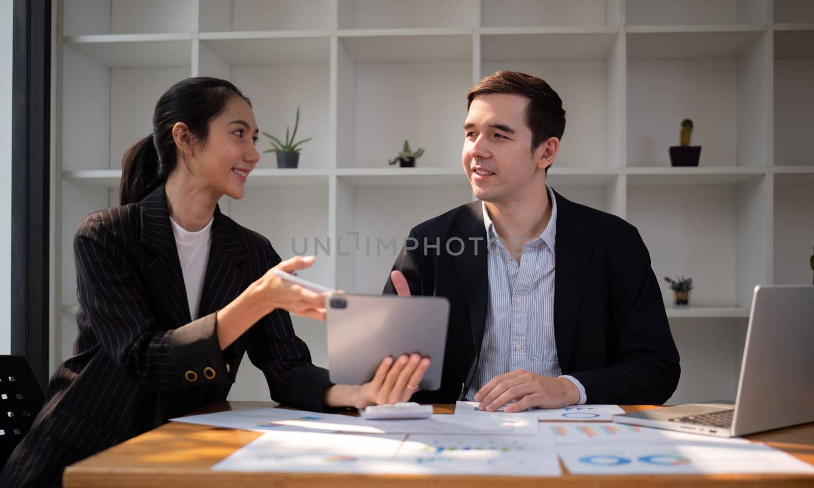 Two businessmen discussing project at the office room Businessman discusses project planning with colleagues in modern workplace while having discussion and advice on financial data report..