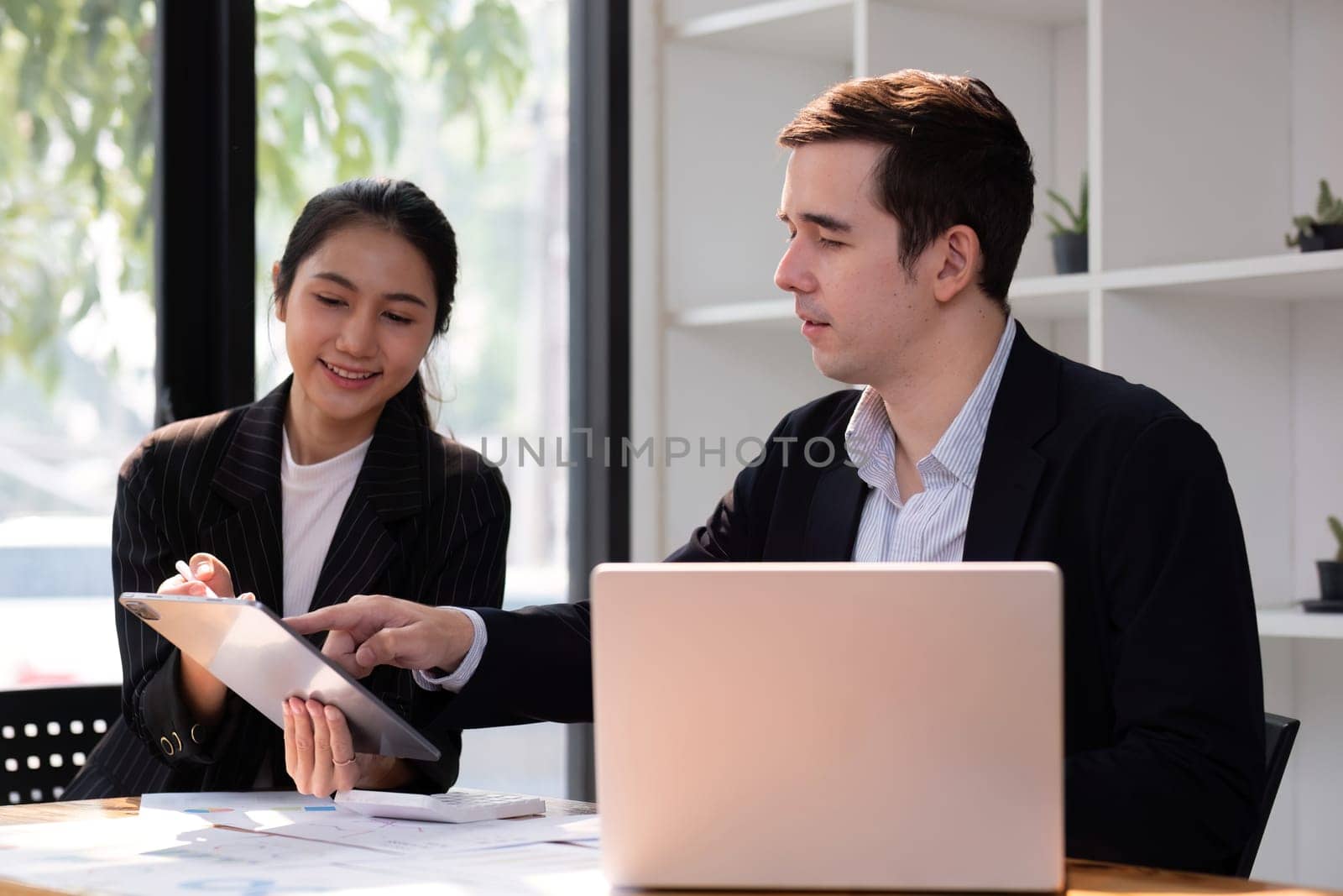 Two businessmen discussing project at the office room Businessman discusses project planning with colleagues in modern workplace while having discussion and advice on financial data report. by wichayada